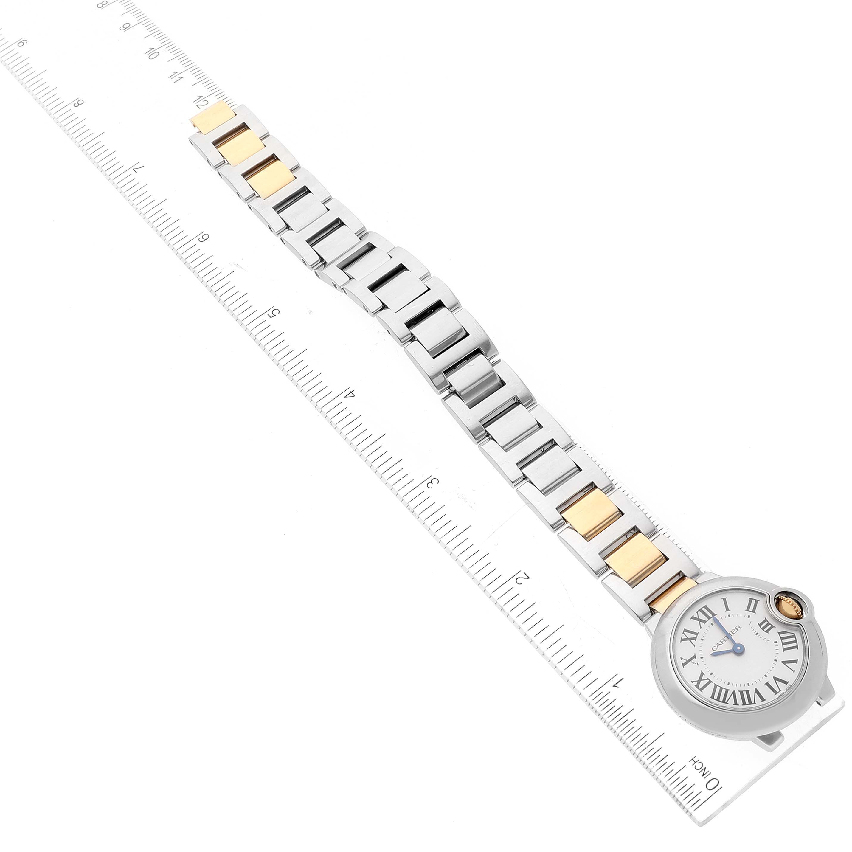 The image shows an overhead view of a Cartier Ballon Bleu W69007Z3 Women
s Steel and Gold (two tone) Silver Dial W69007Z3 Women
s Steel and Gold (two tone) Silver Dial watch next to a ruler, displaying its bracelet and watch face.
