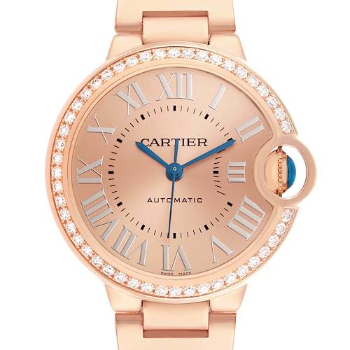 The Cartier Ballon Bleu WJBB0077 Women's Yellow Gold Pink Dial watch is shown from the front, highlighting its round face, gemstone accents, and Roman numerals.