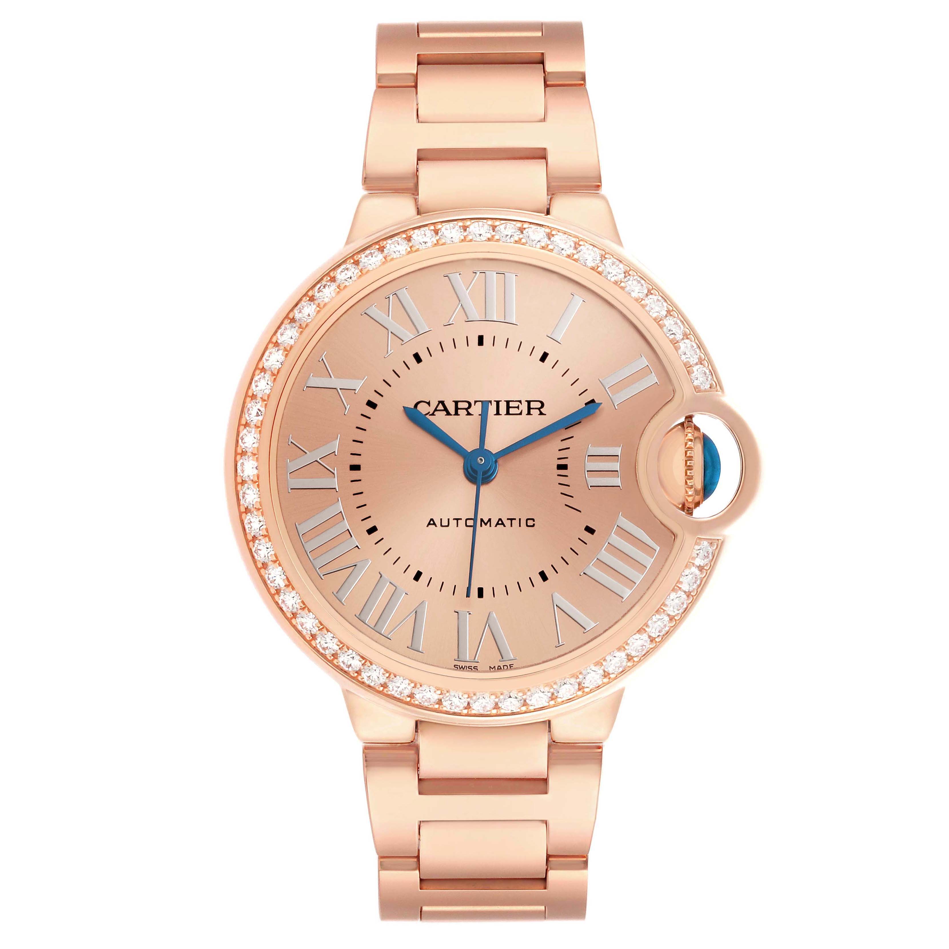 The Cartier Ballon Bleu WJBB0077 Women's Yellow Gold Pink Dial watch is shown from a front angle, highlighting its round case, Roman numerals, blue hands, and bracelet.