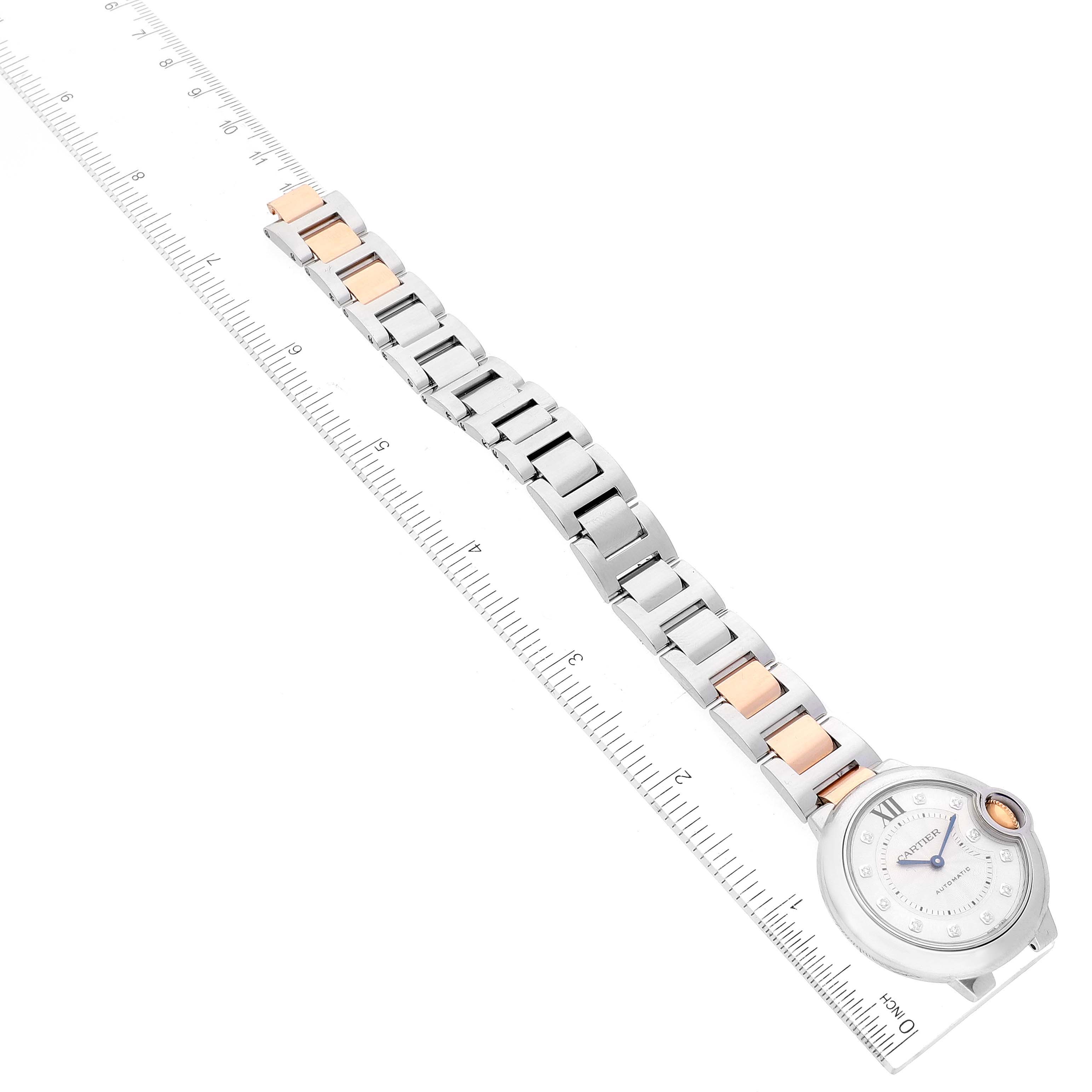 The image shows a top-down view of a Cartier Ballon Bleu WE902061 Women
s Stainless Steel Silver Dial WE902061 Women
s Stainless Steel Silver Dial watch with a ruler for scale, displaying its face and metal bracelet.