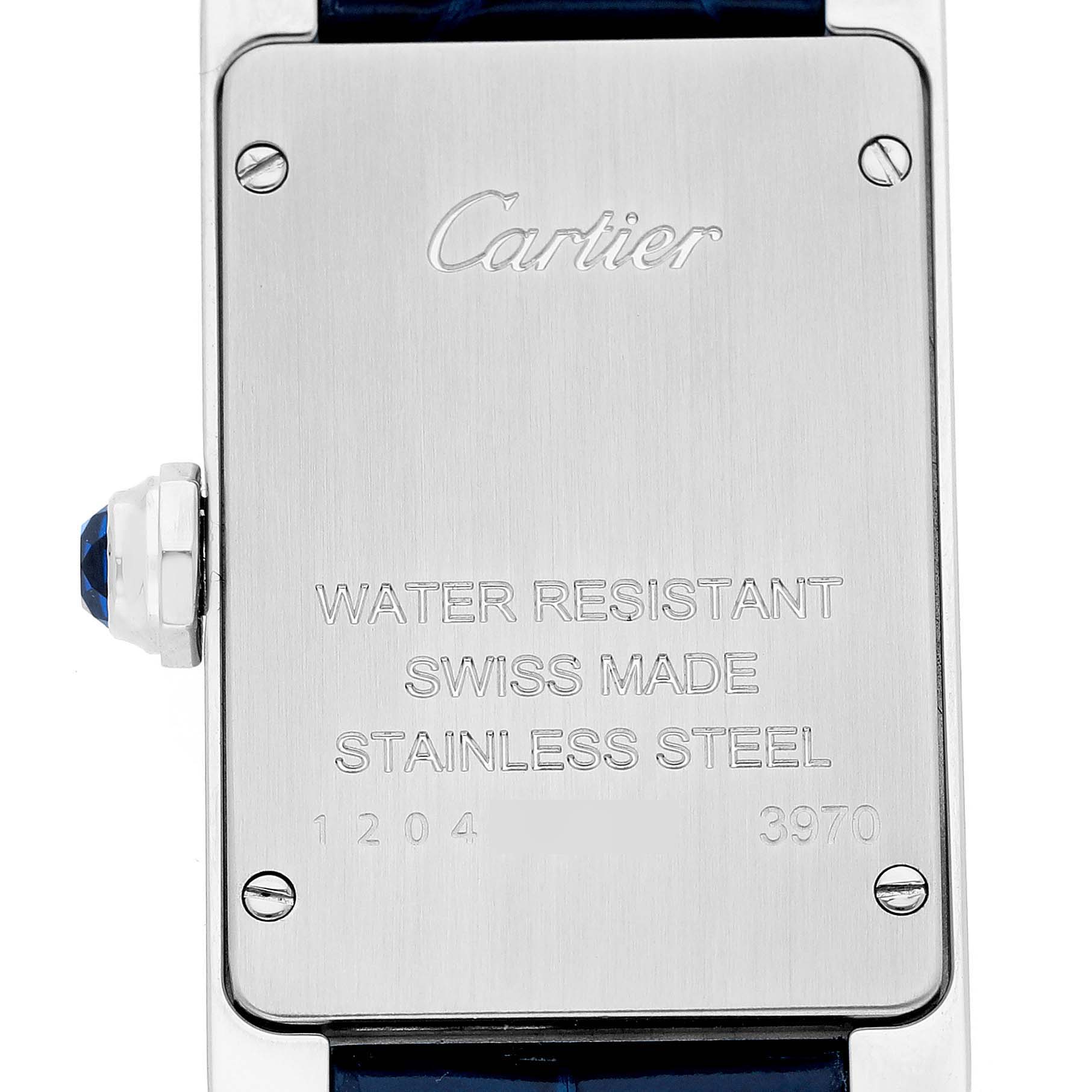 The image shows the back case of the Cartier Tank Americaine WSTA0016 Women's Stainless Steel Silver Dial watch, featuring engraved text and a blue cabochon on the crown.
