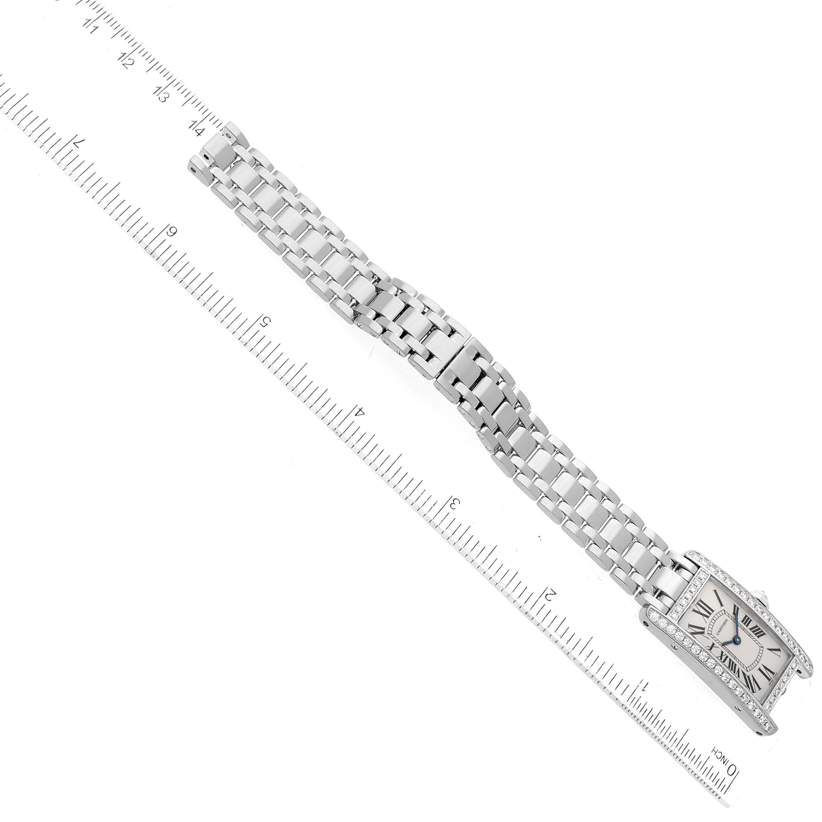 The Cartier Tank Americaine WB7073L1 Women's Stainless Steel Silver Dial WB7073L1 Women's Stainless Steel Silver Dial watch is shown from a top view, displaying the face and stainless steel bracelet alongside a ruler.