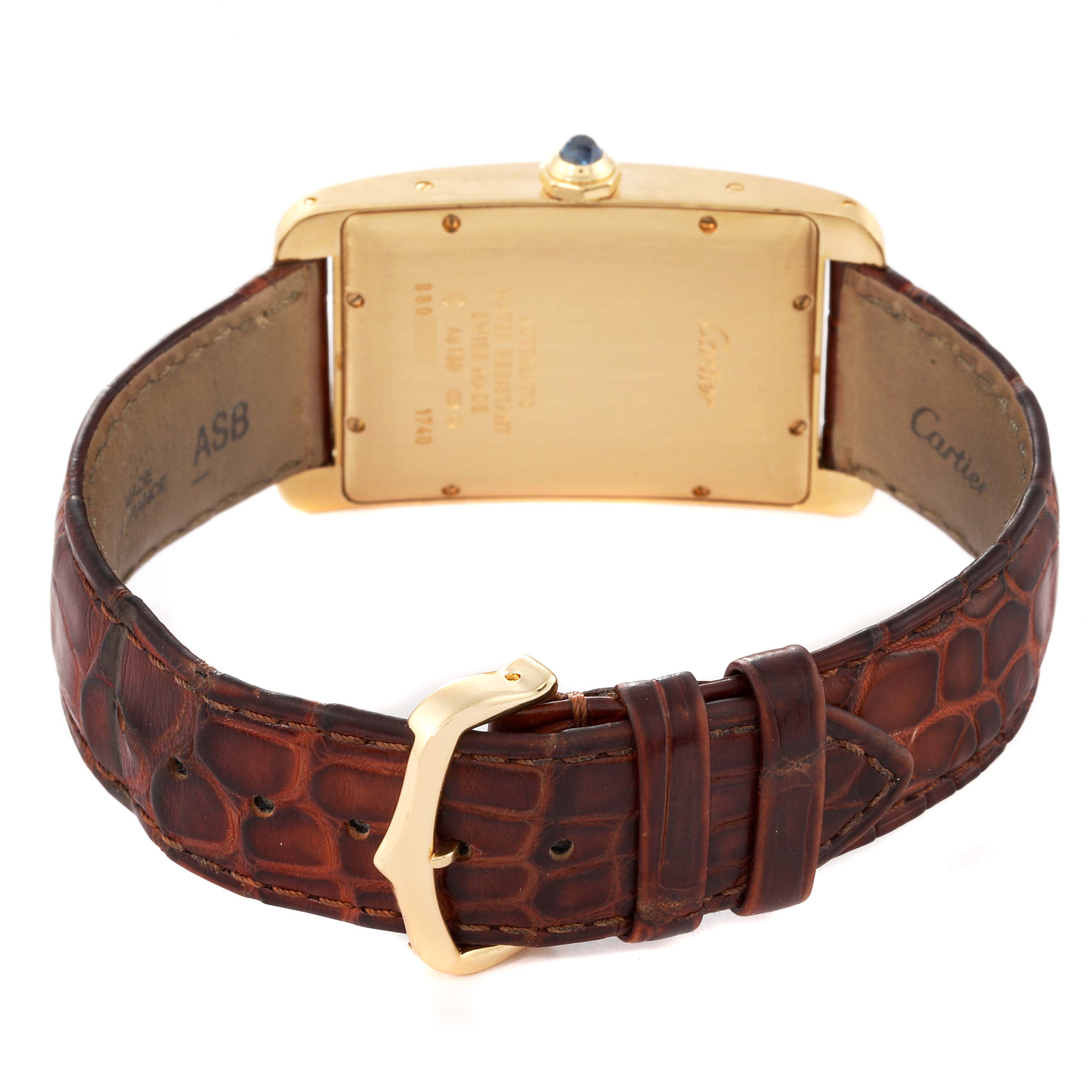 The image shows the back view of a Cartier Tank Americaine W2603156 Men
s Yellow Gold Silver Dial W2603156 Men
s Yellow Gold Silver Dial watch, highlighting its golden case and brown leather strap with a buckle.