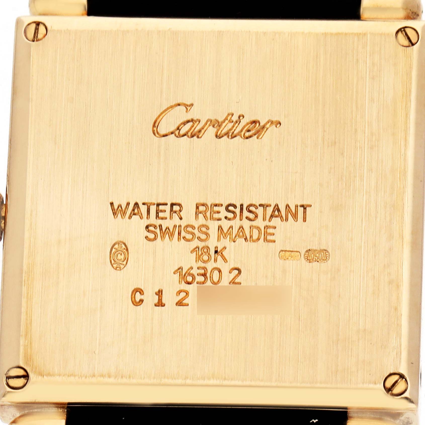 The image shows the back side of a Cartier Tank Obus W1512256 Women
s Yellow Gold Silver Dial watch, highlighting the case with engravings.