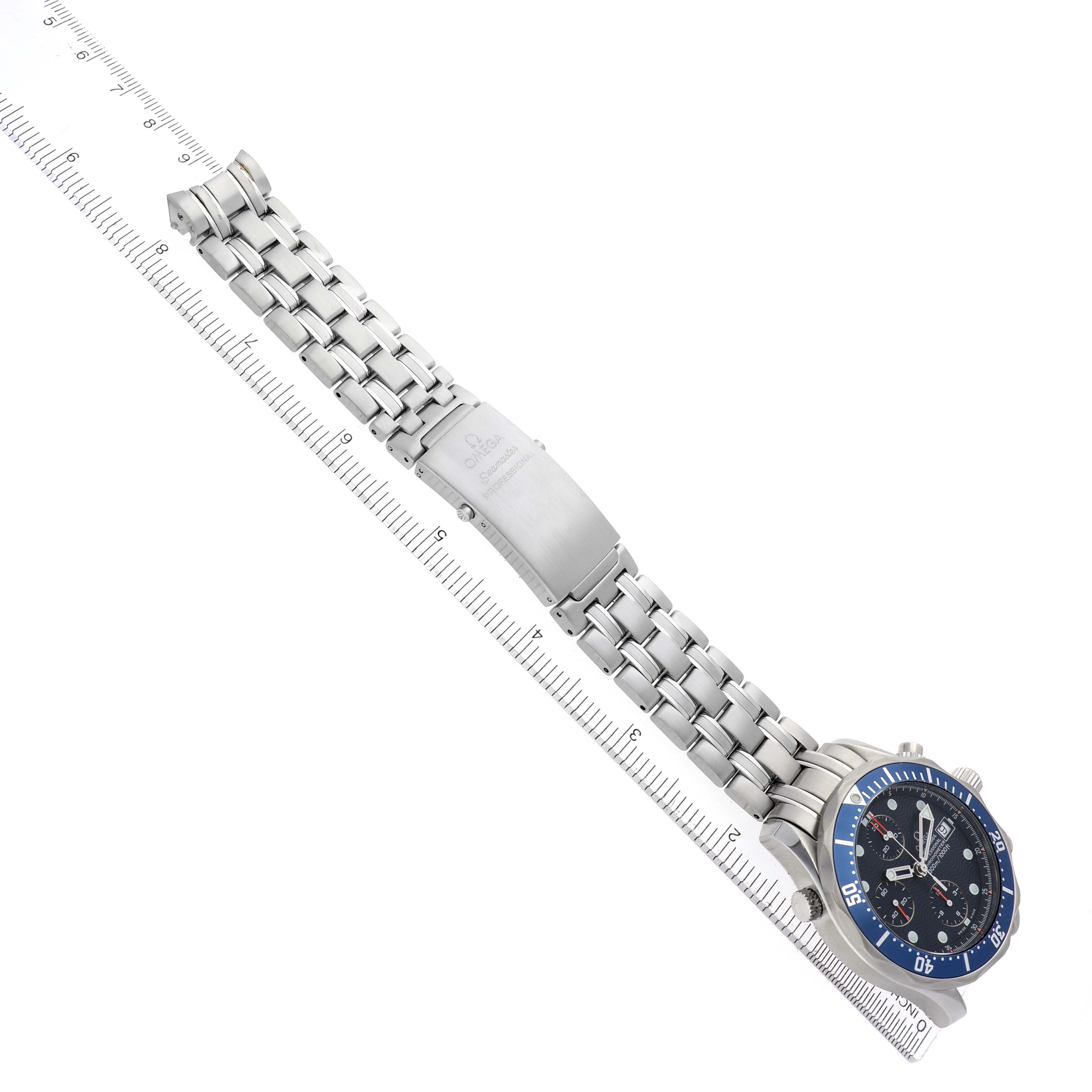 The Omega Seamaster 2599.80.00 Men
s Stainless Steel Blue Dial watch is shown diagonally with its bracelet, clasp, and face visible, aligned next to a ruler.