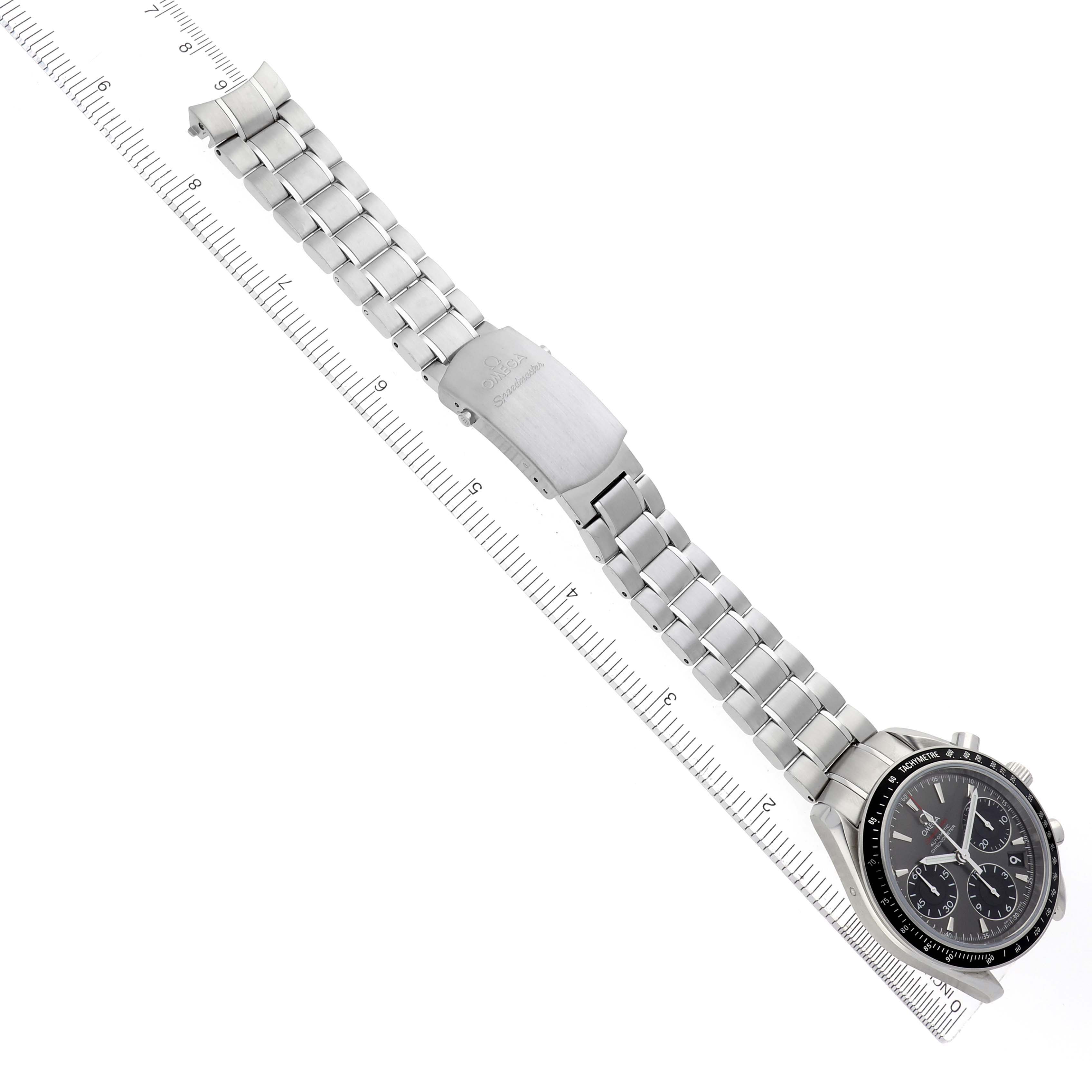 The Omega Speedmaster 323.30.40.40.06.001 Men
s Stainless Steel Grey Dial watch is shown flat with a metal bracelet and clasp, alongside a ruler for scale.