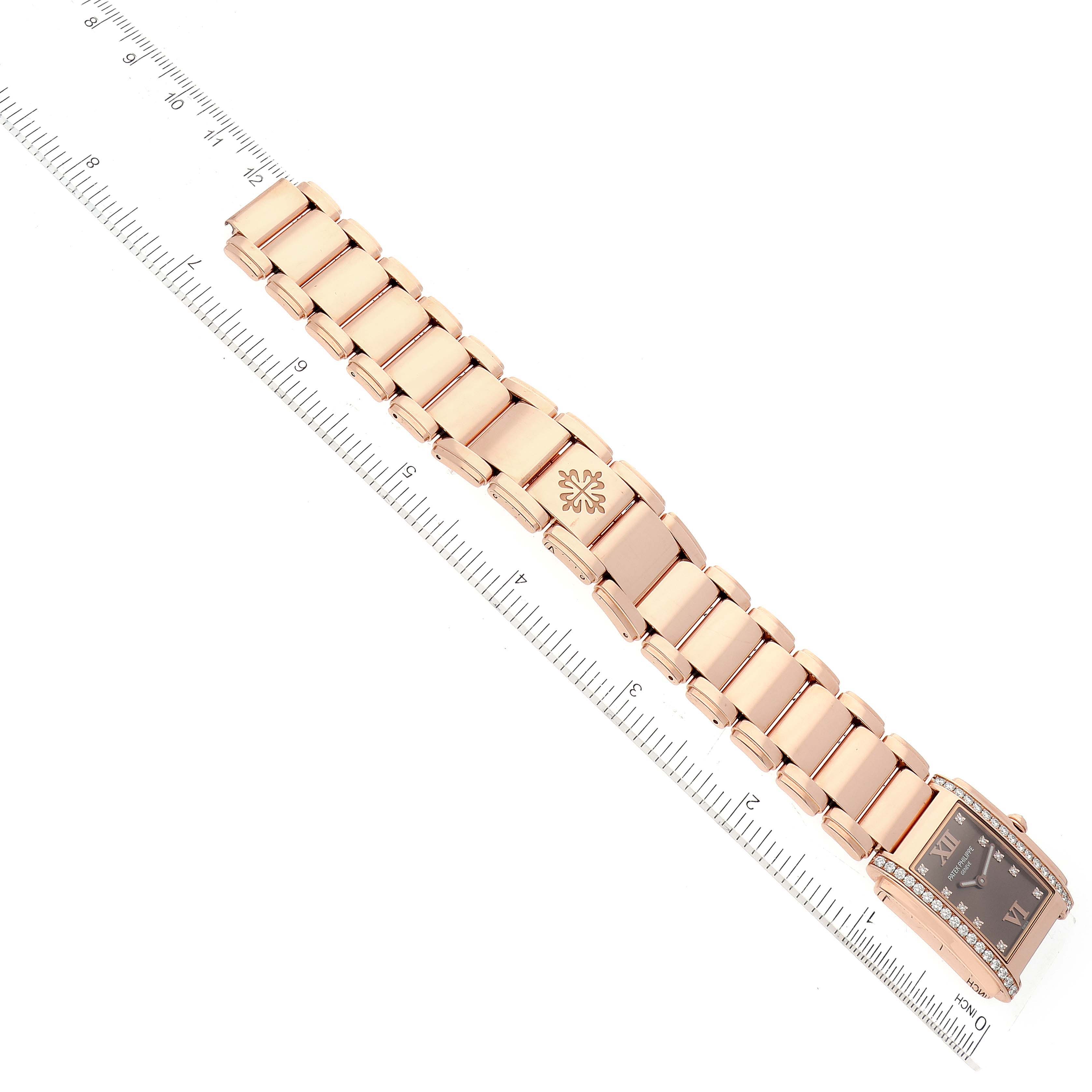 The Patek Philippe Twenty-4 4910/11R Women's Rose Gold Brown Dial 4910/11R Women's Rose Gold Brown Dial watch is shown from a top-down angle, displaying the entire band and face, with a ruler for scale.