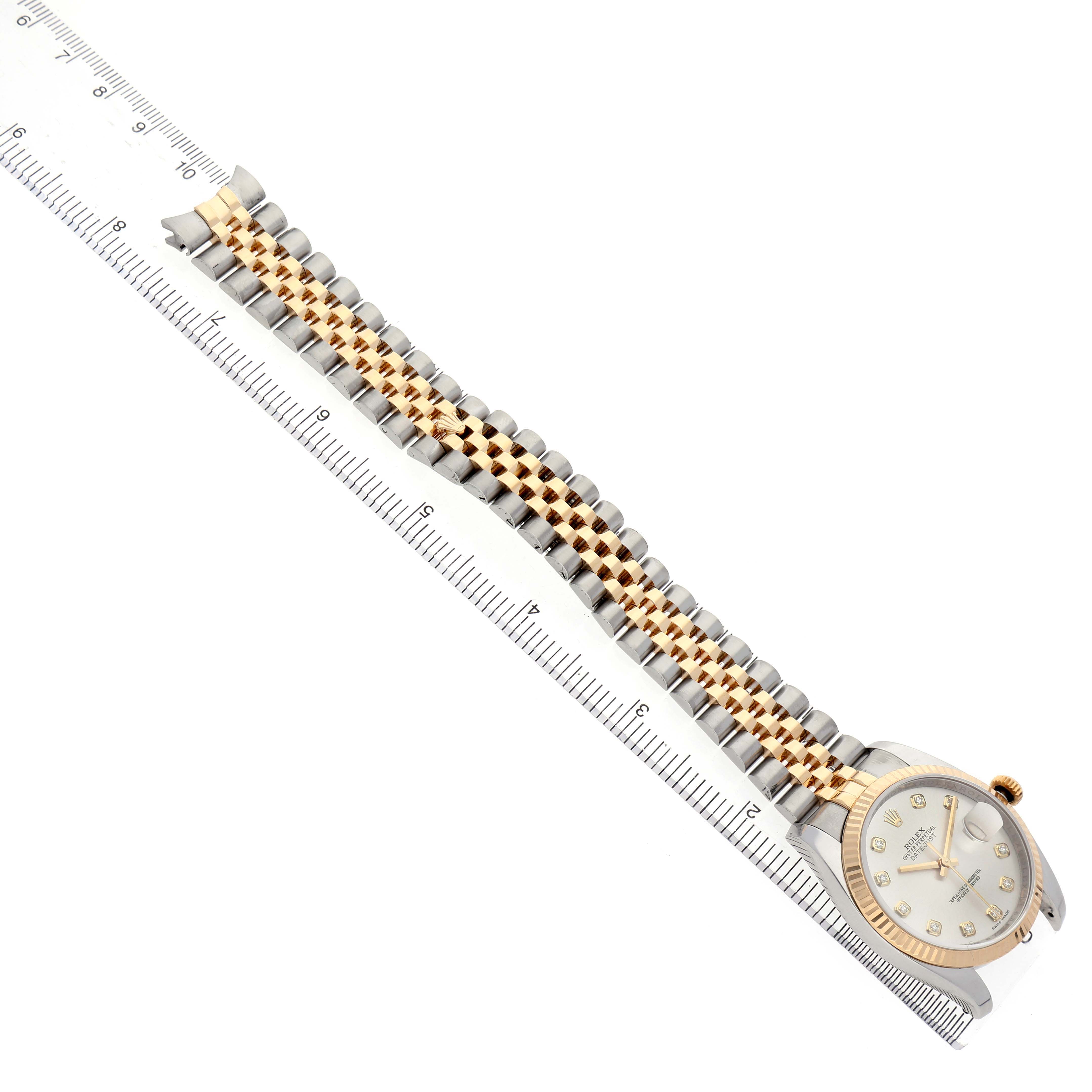 The Rolex Datejust 116233 Men's Steel and Gold (two tone) Silver Dial watch is shown at a diagonal angle displaying the bracelet and face next to a ruler.