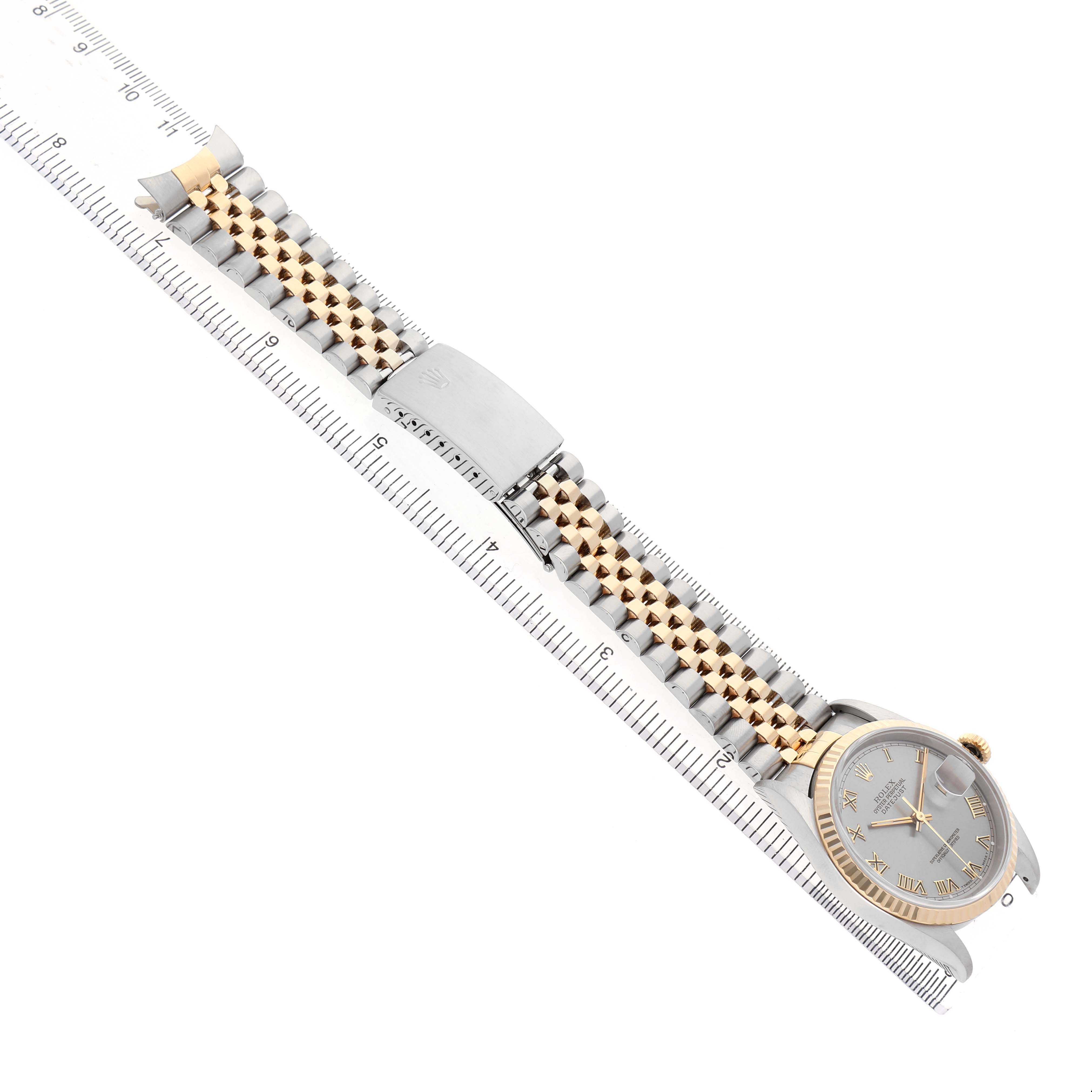 The Rolex Datejust 16233 Men's Stainless Steel Grey Dial watch is shown from an angled top view, displaying its face, bracelet, and clasp laid next to a ruler.