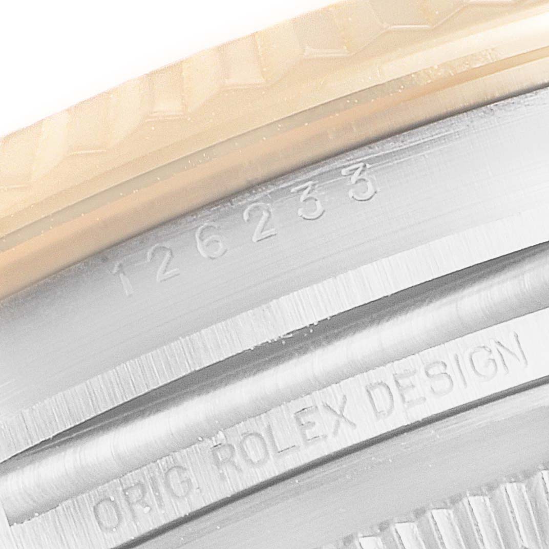 This image shows a close-up of the serial number and "ORIG ROLEX DESIGN" engraving on a Rolex Datejust 126233 Men's Steel and Gold (two tone) White Dial 126233 Men's Steel and Gold (two tone) White Dial model case.