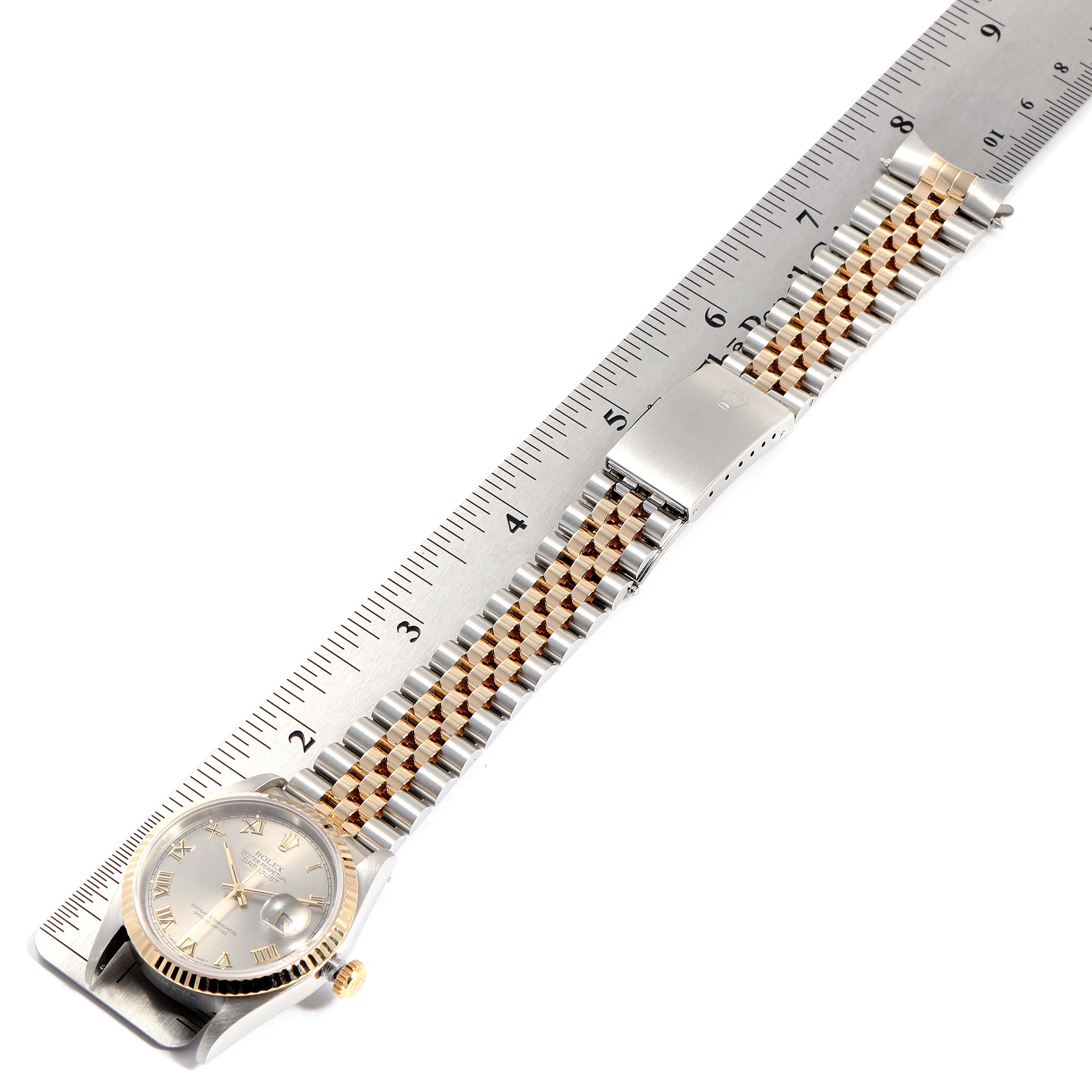 The Rolex Datejust 16233 Men
s Steel and Gold (two tone) Grey Dial 16233 Men
s Steel and Gold (two tone) Grey Dial watch is shown flat on a ruler, displaying the face, band, and clasp.