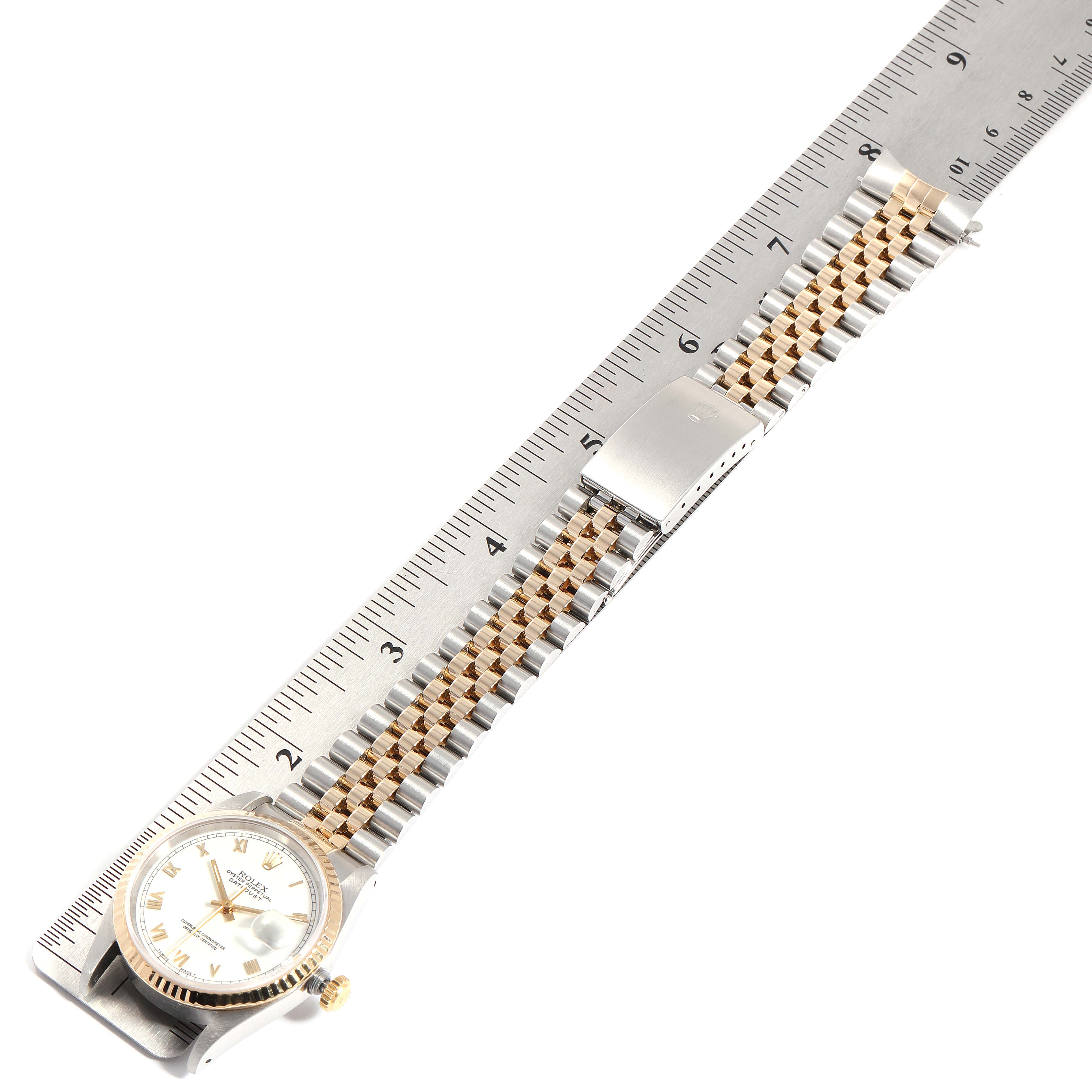 The Rolex Datejust 16233 Men
s Steel and Gold (two tone) White Dial 16233 Men
s Steel and Gold (two tone) White Dial watch is shown from a top-down angle against a ruler, highlighting its face and a two-tone metal bracelet.