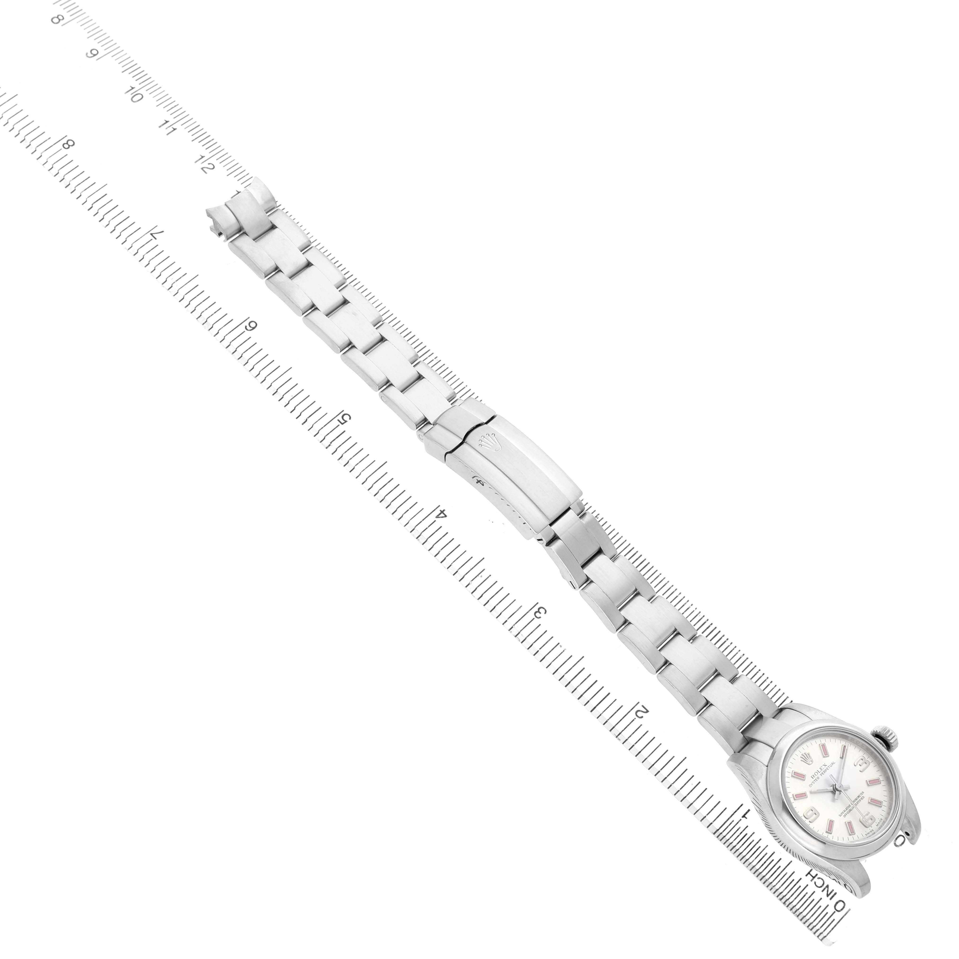 The Rolex Oyster Perpetual 176200 Women's Stainless Steel Silver Dial watch is shown at an angled top view, highlighting the bracelet, clasp, and face alongside a ruler for scale.
