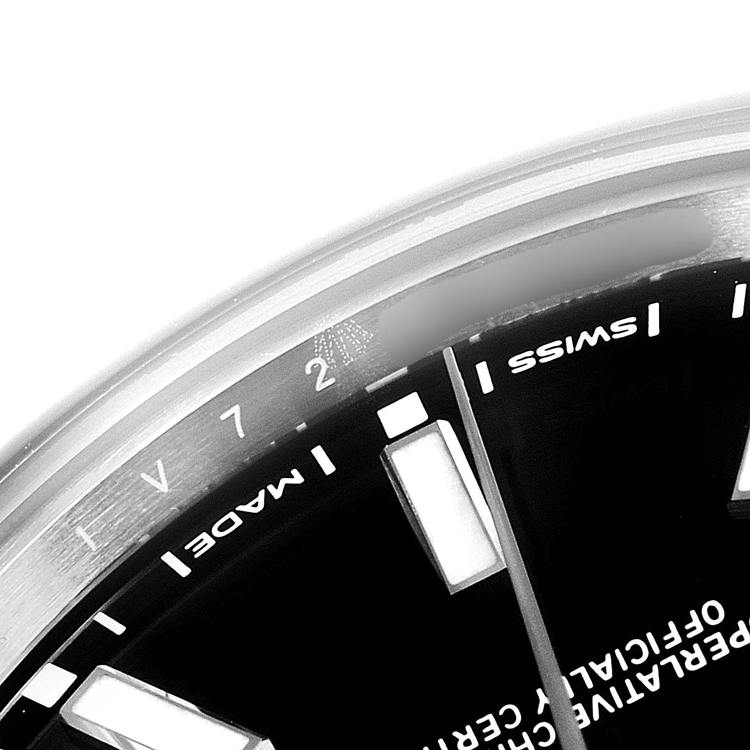 The close-up image shows a portion of the dial and bezel of a Rolex Oyster Perpetual 114300 Men's Stainless Steel Black Dial 114300 Men's Stainless Steel Black Dial watch, displaying its markings and indices.