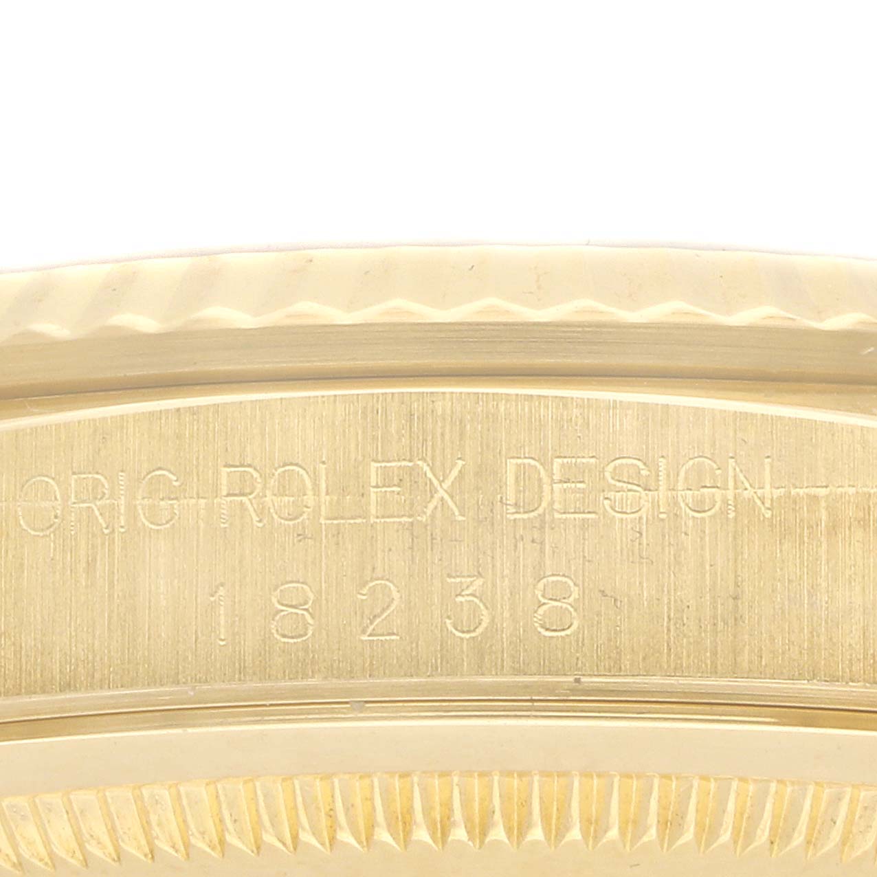 The image shows a close-up of the side of a Rolex President 18238 Men
s Yellow Gold Champagne Dial model, highlighting the engraved text and fluted bezel.