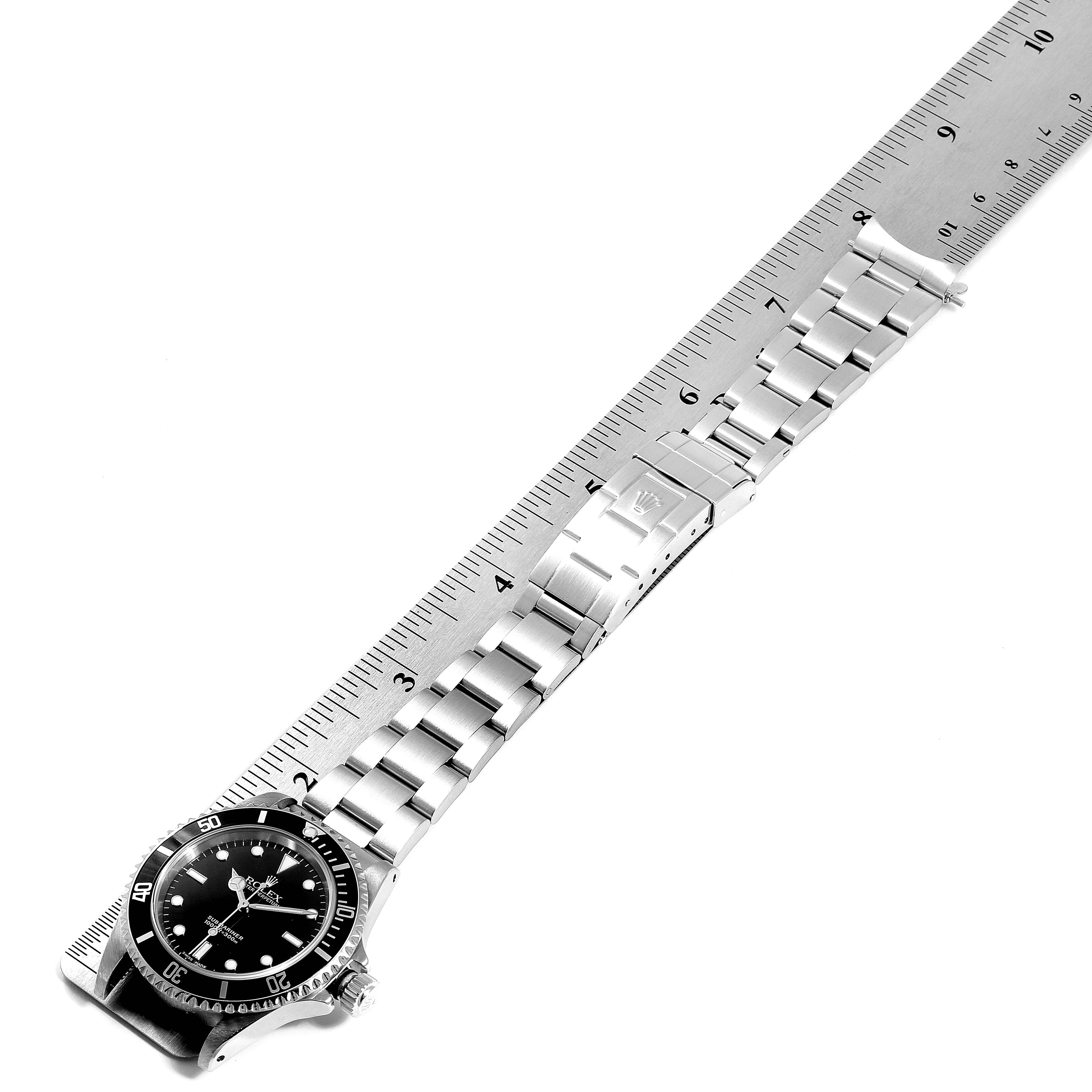 The image shows a top-down view of a Rolex Submariner 14060 Men
s Stainless Steel Black Dial 14060 Men
s Stainless Steel Black Dial watch with its band laid flat on a ruler.