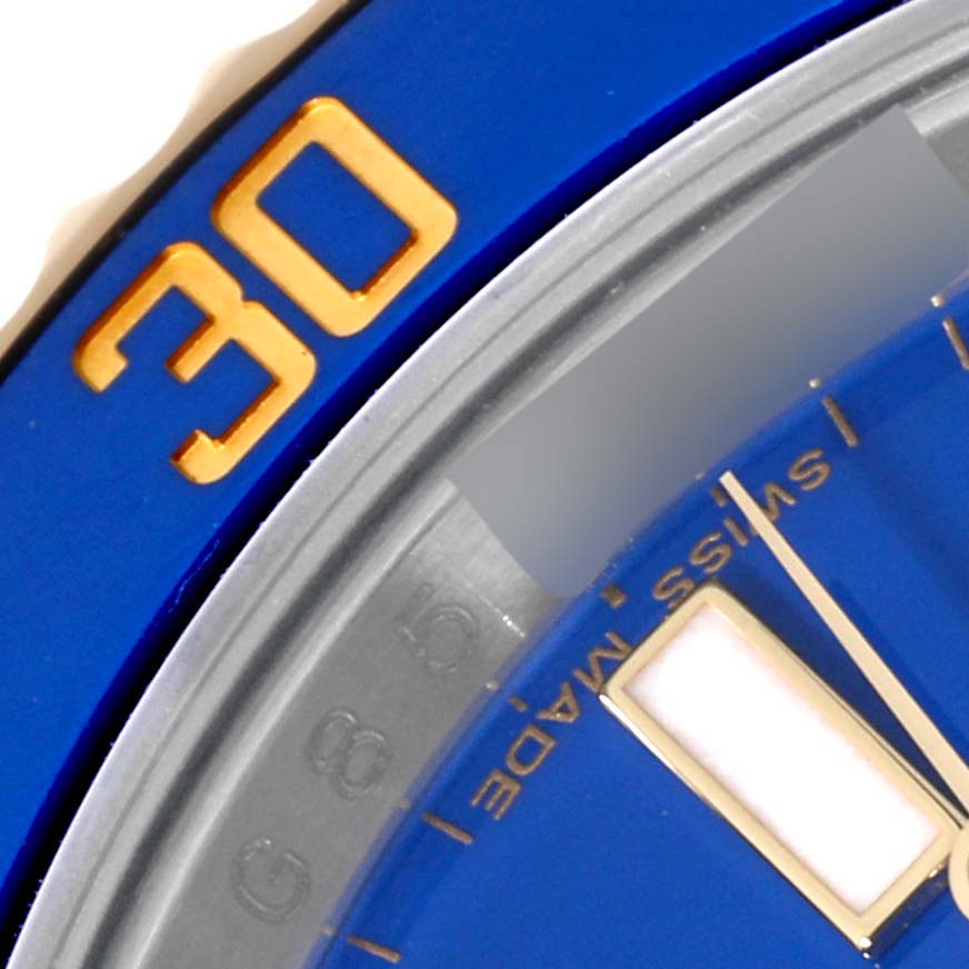 This is a close-up image of a Rolex Submariner 116613 Men's Steel and Gold (two tone) Blue Dial 116613 Men's Steel and Gold (two tone) Blue Dial watch showing parts of the bezel, dial, and minute hand.