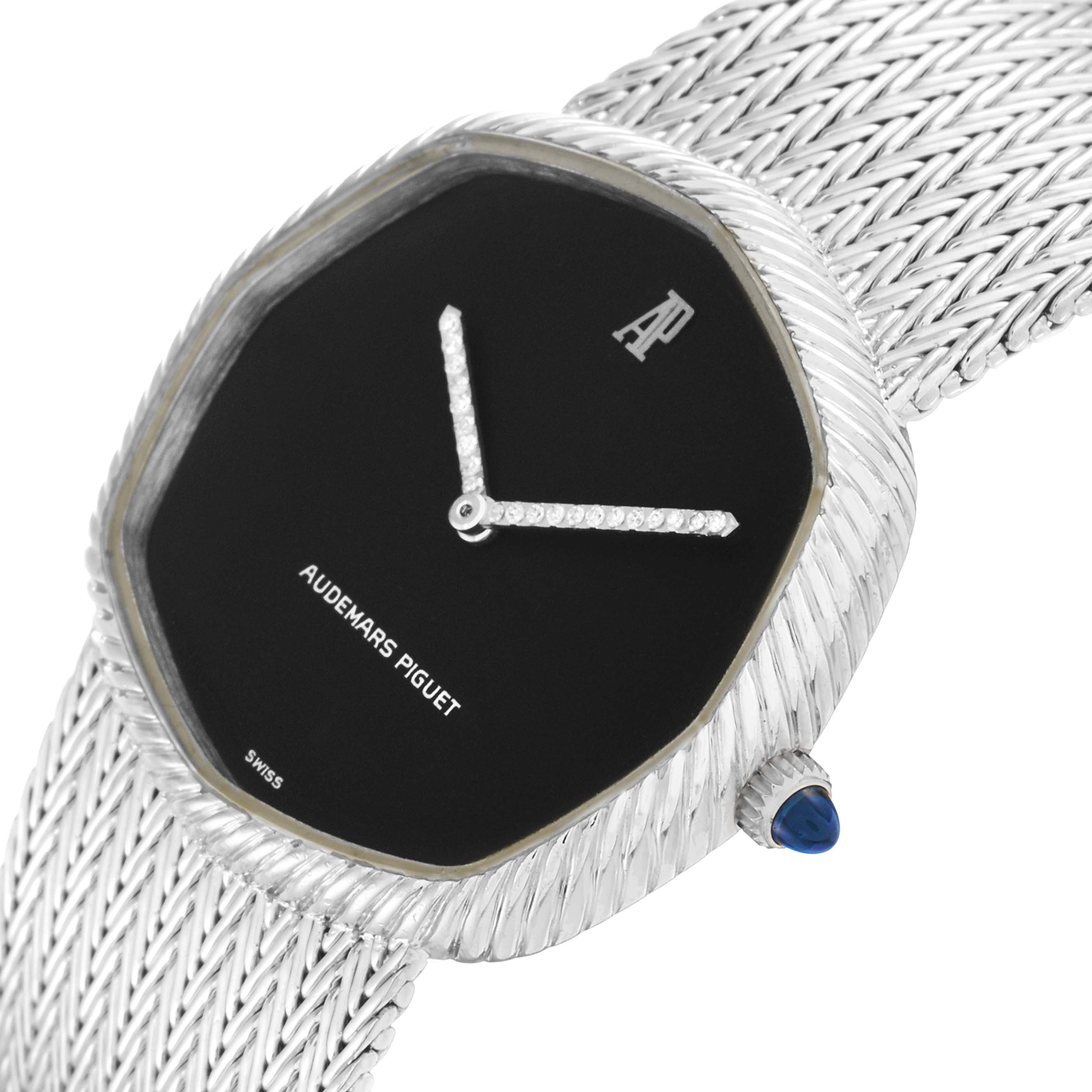 The Audemars Piguet Vintage Women
s White Gold Black Dial watch is shown at an angled close-up, highlighting the woven bracelet, black dial, and crown with a blue cabochon.