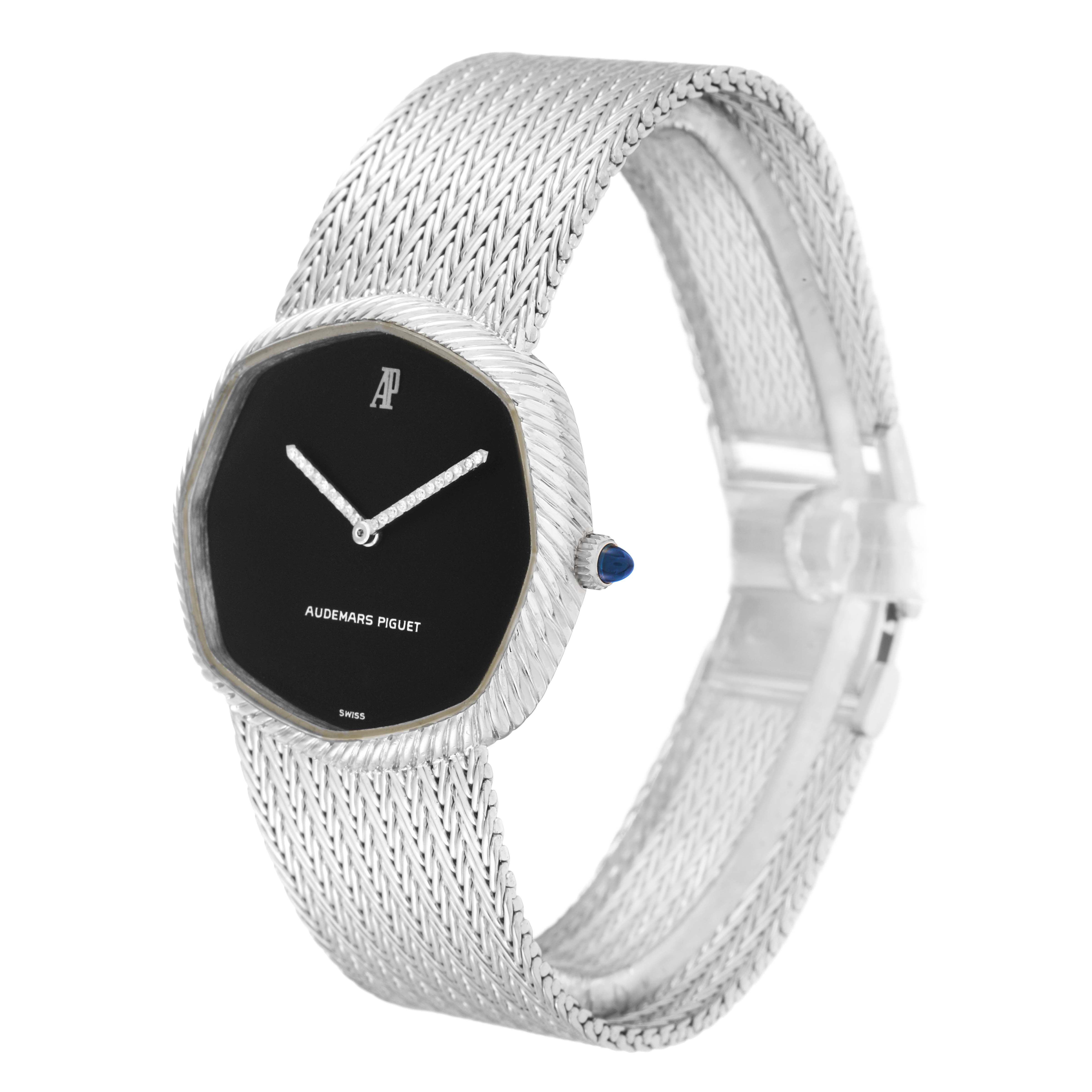 The Audemars Piguet Vintage Women
s White Gold Black Dial model watch is shown from a three-quarter angle, highlighting its black dial, octagonal case, crown, and woven bracelet.