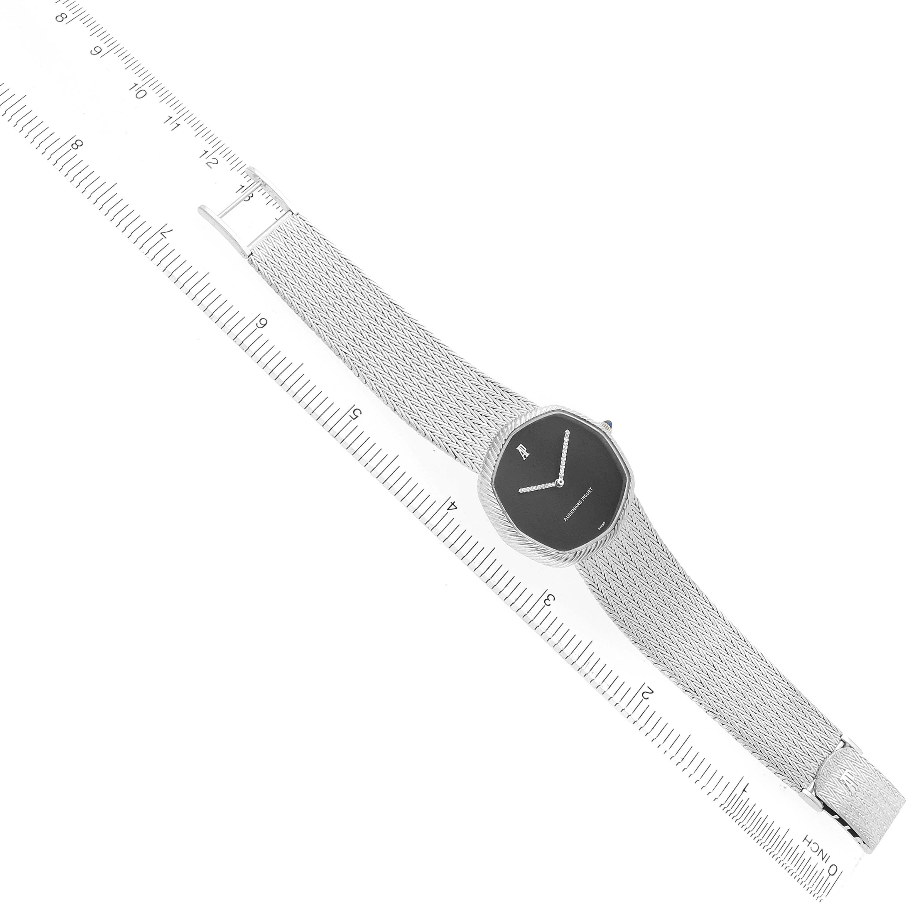 The Audemars Piguet Vintage Women
s White Gold Black Dial watch is shown at an angle, displaying its face, mesh strap, and clasp parallel to a ruler for scale.