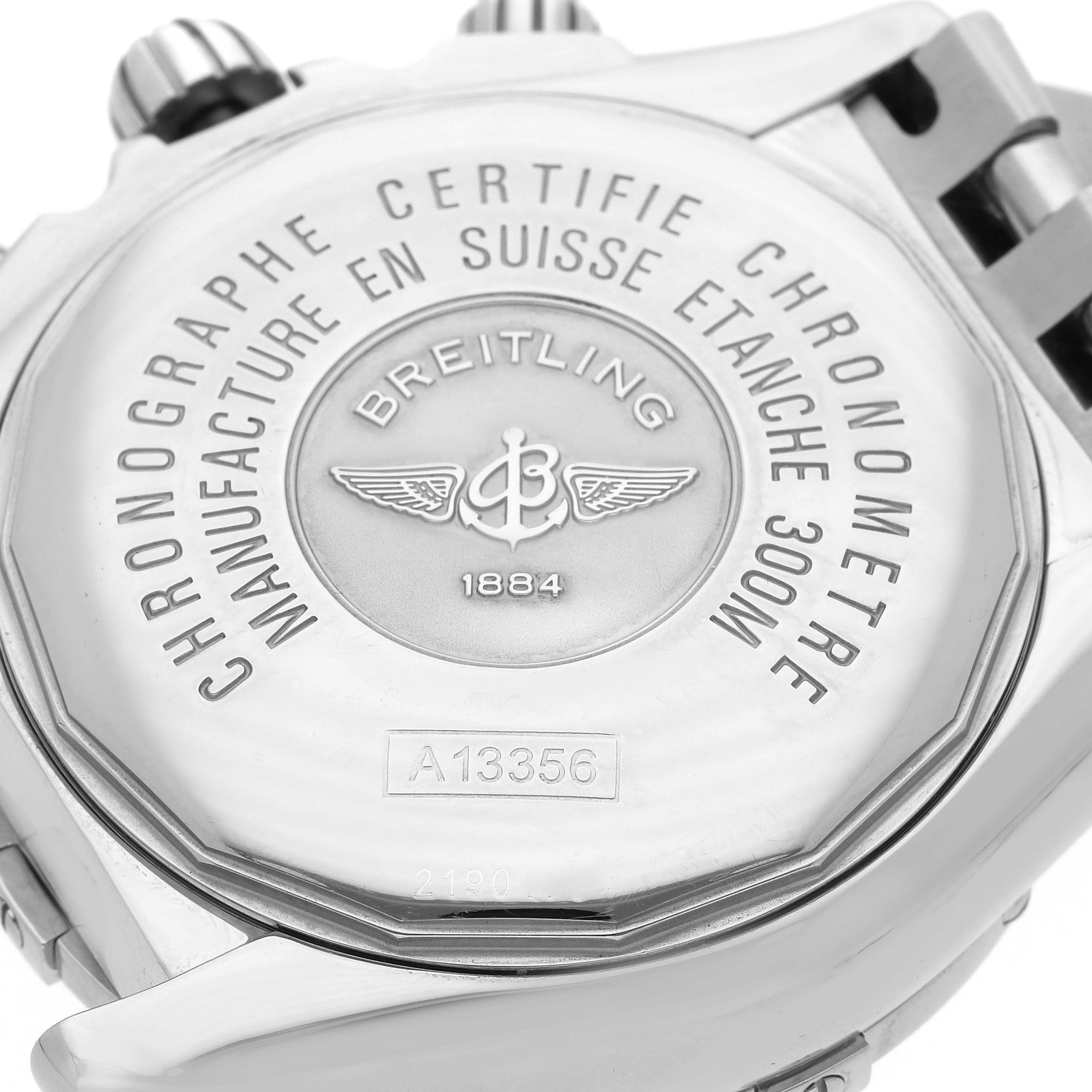 The image shows the back of a Breitling Chronomat A13356 Men
s Stainless Steel Black Dial watch, highlighting its engravings and metal bracelet attachment.
