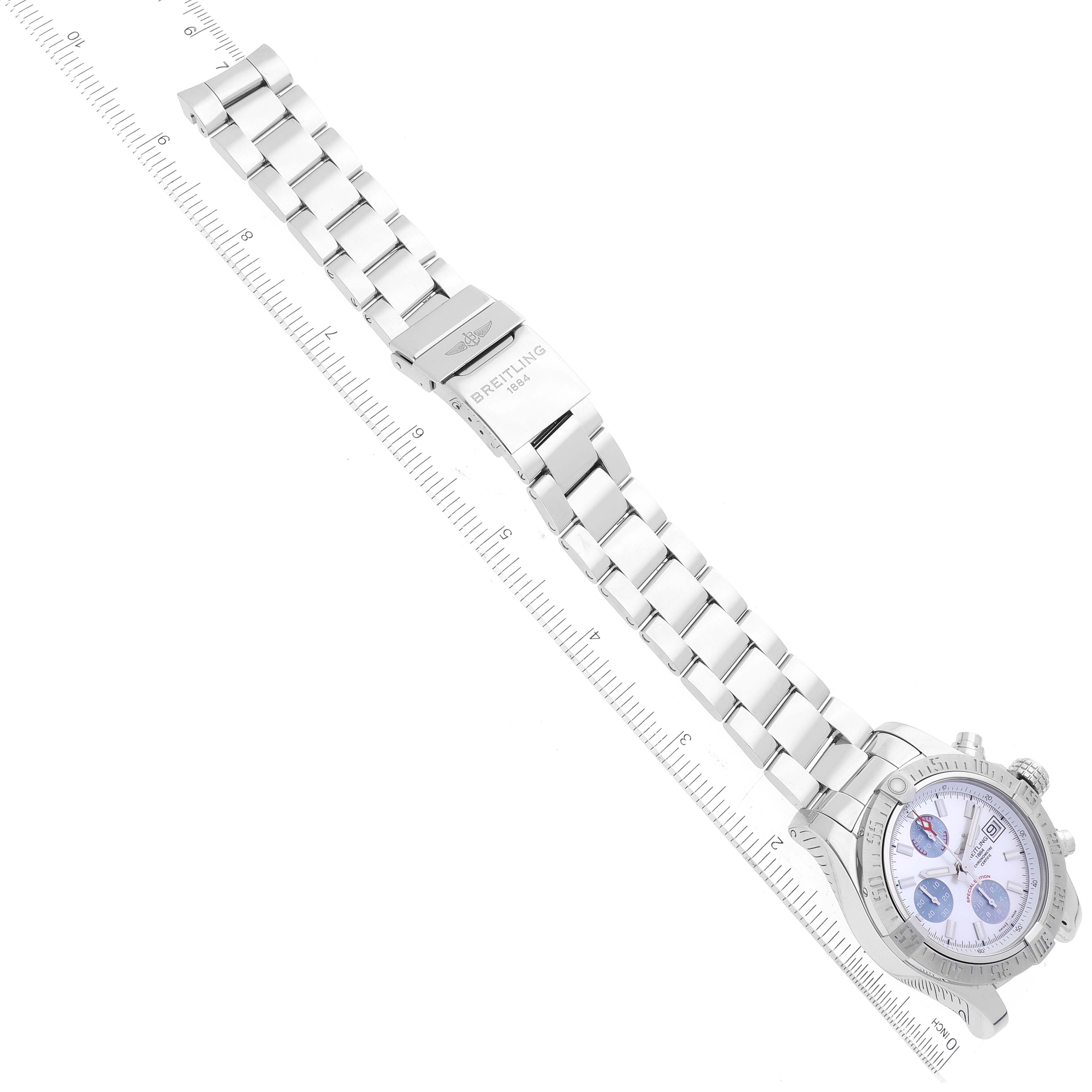 The Breitling Avenger A13381 Men's Stainless Steel Mother of Pearl Dial A13381 Men's Stainless Steel Mother of Pearl Dial watch is shown from a top-down angle, displaying its bracelet, clasp, and dial next to a measuring scale.