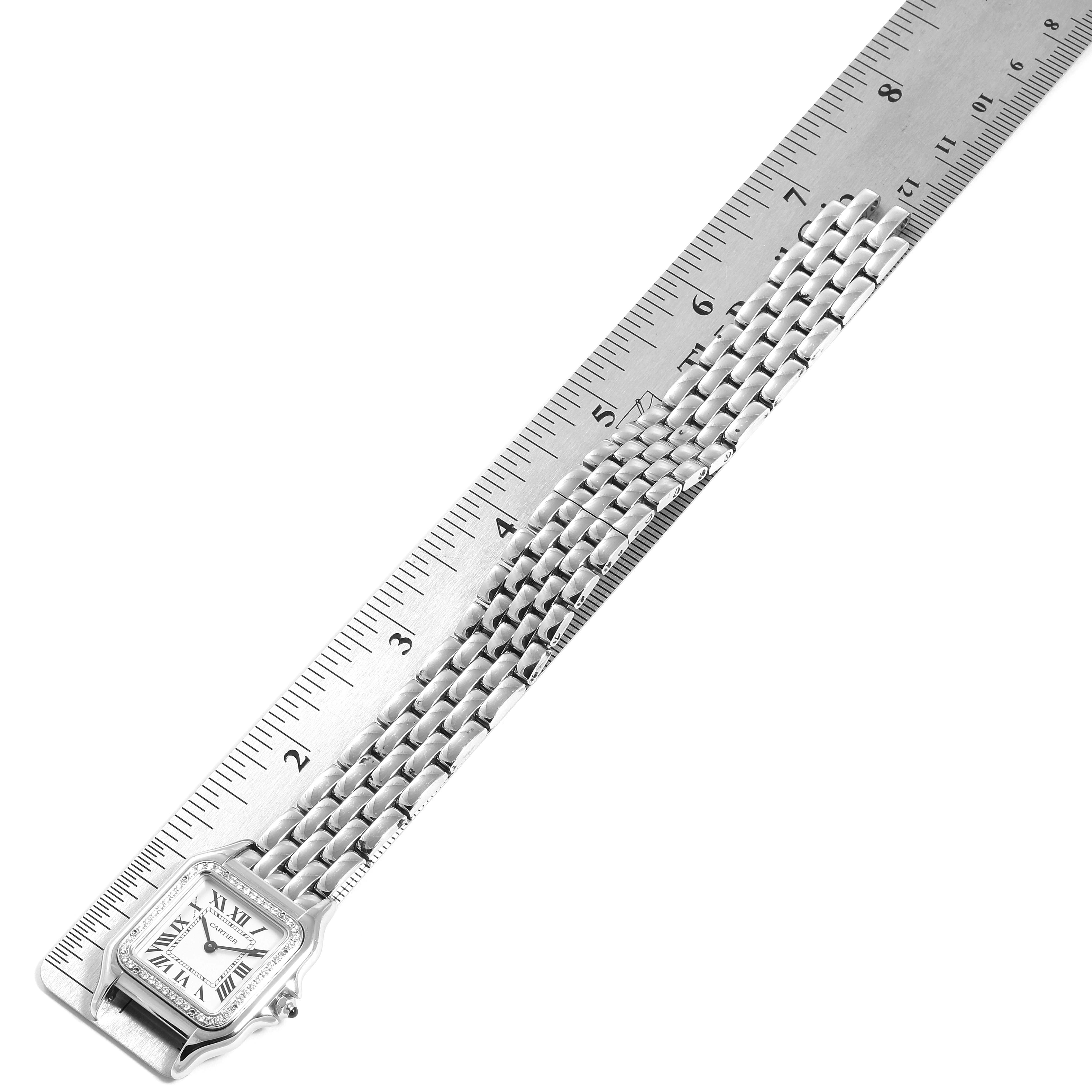 The image shows a Panthere model by Cartier laid flat next to a ruler, showcasing its watch face and metal bracelet.