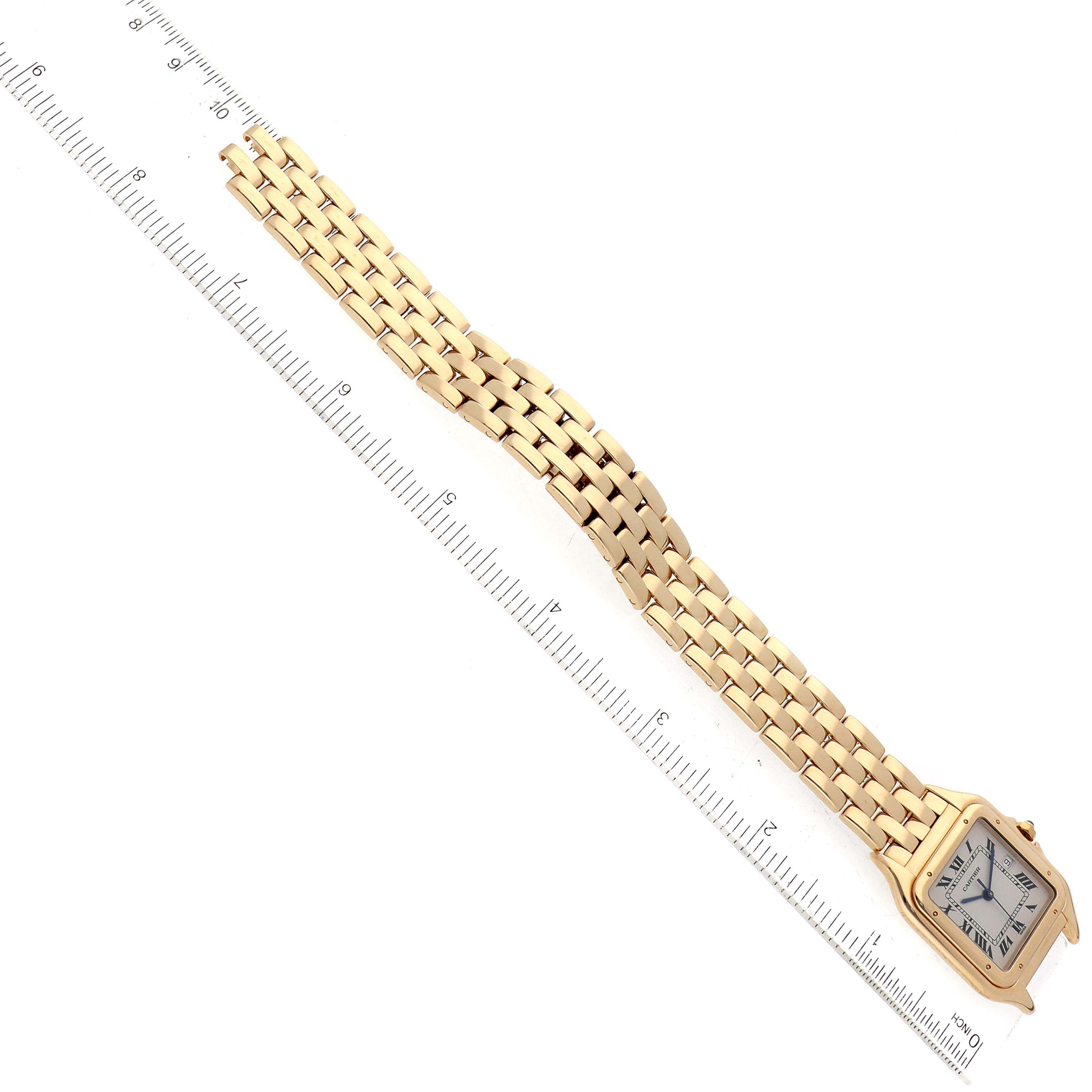 This Cartier Panthere W25014B9 Men
s Yellow Gold Silver Dial W25014B9 Men
s Yellow Gold Silver Dial watch is shown from an overhead angle, highlighting its face and linked bracelet alongside a ruler for scale.