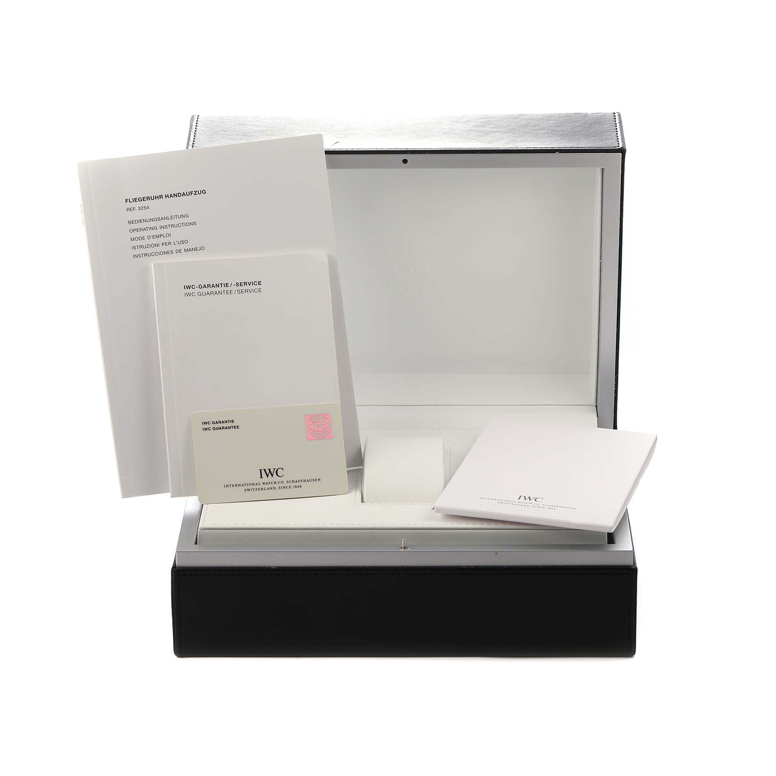 The image shows the open box and documentation for the IWC Pilot IW325401 Men
s Platinum Black Dial watch, angled to reveal its interior and booklets.