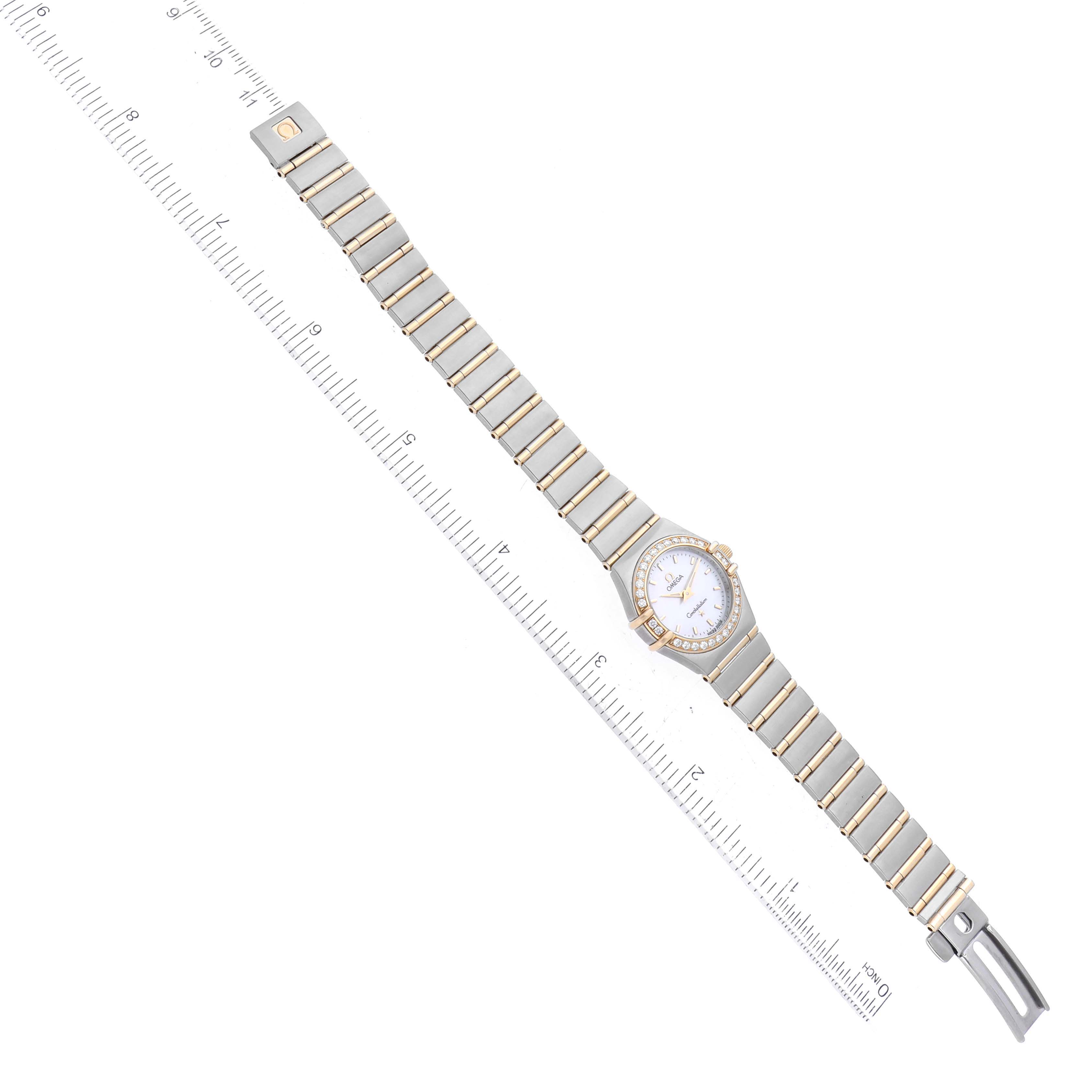 This image shows the Omega 1267.70.00 Women's Steel and Gold (two tone) Mother of Pearl Dial 1267.70.00 Women's Steel and Gold (two tone) Mother of Pearl Dial Constellation Steel Yellow Gold Mother of Pearl Diamond Watch 1267.70.00 laid flat with a ruler for scale.