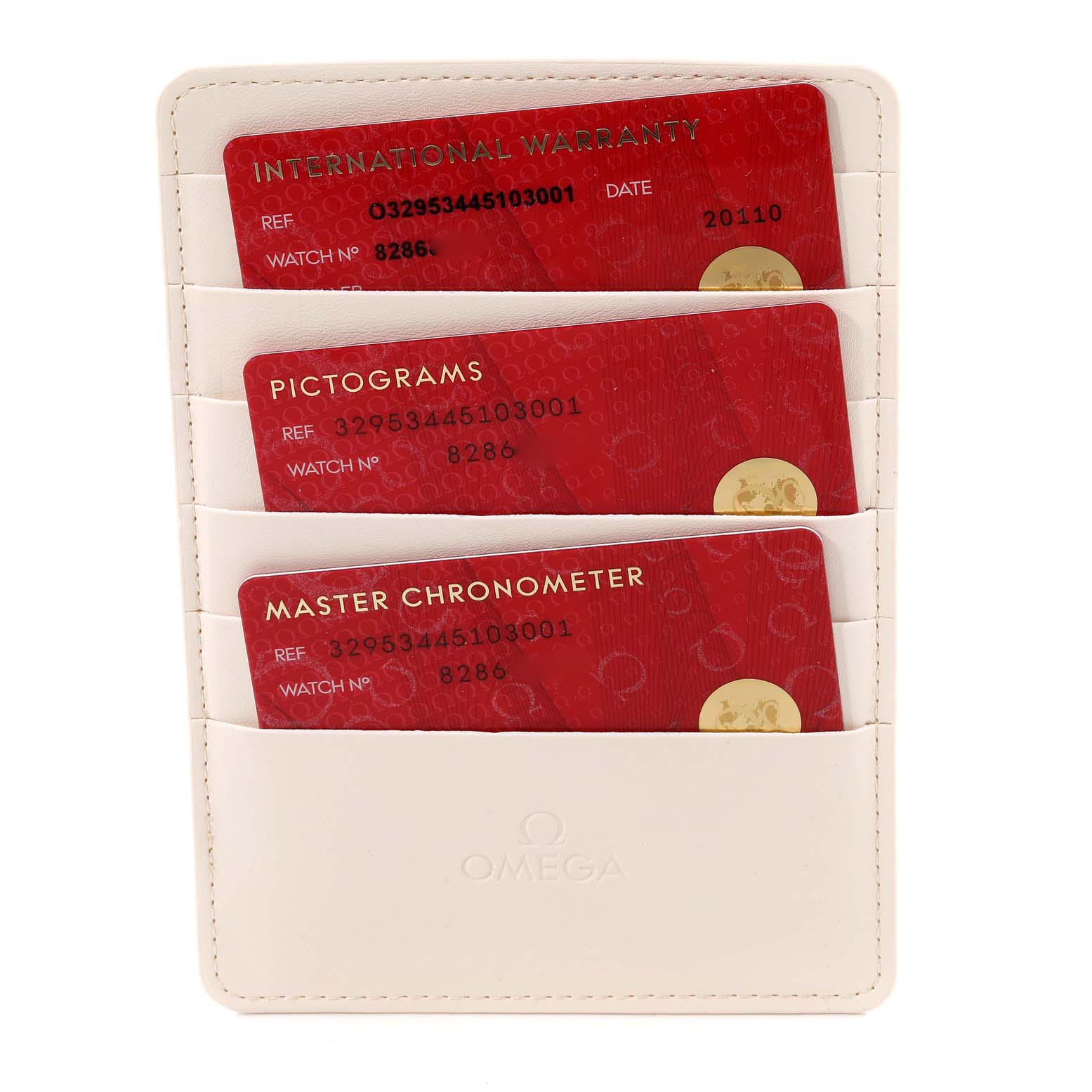 The image shows three red cards titled "International Warranty," "Pictograms," and "Master Chronometer" inside a white Omega wallet for the Speedmaster model.