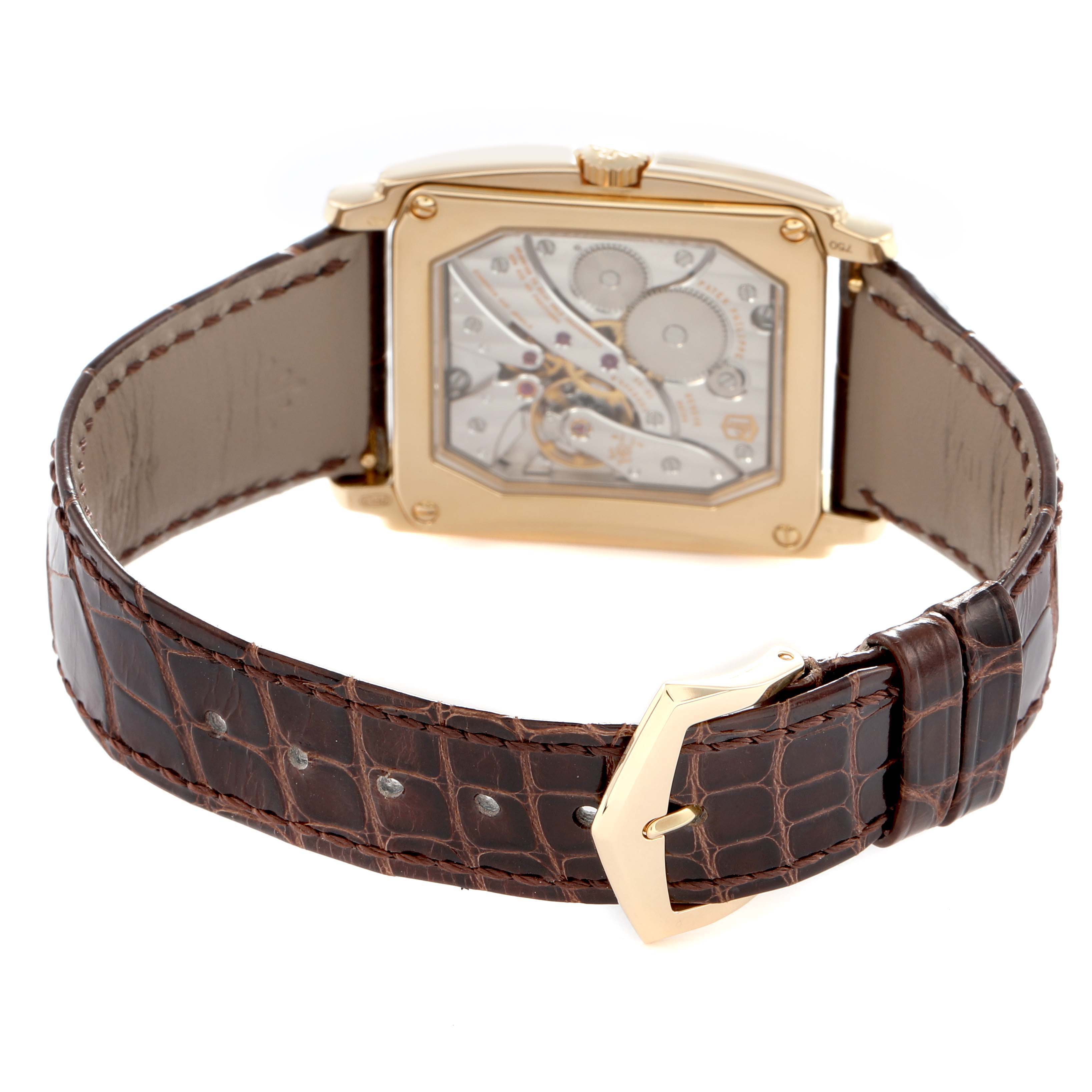 The image shows the back of a Patek Philippe Gondolo 5124 Men
s Yellow Gold Silver Dial watch, highlighting the movement and a brown leather strap with a gold buckle.