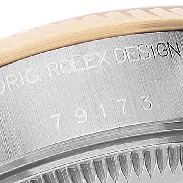 This close-up image shows the side of the Rolex Datejust 79173 Women
s Steel and Gold (two tone) Grey Dial 79173 Women
s Steel and Gold (two tone) Grey Dial model, focusing on the bezel and engraved part of the watch casing.