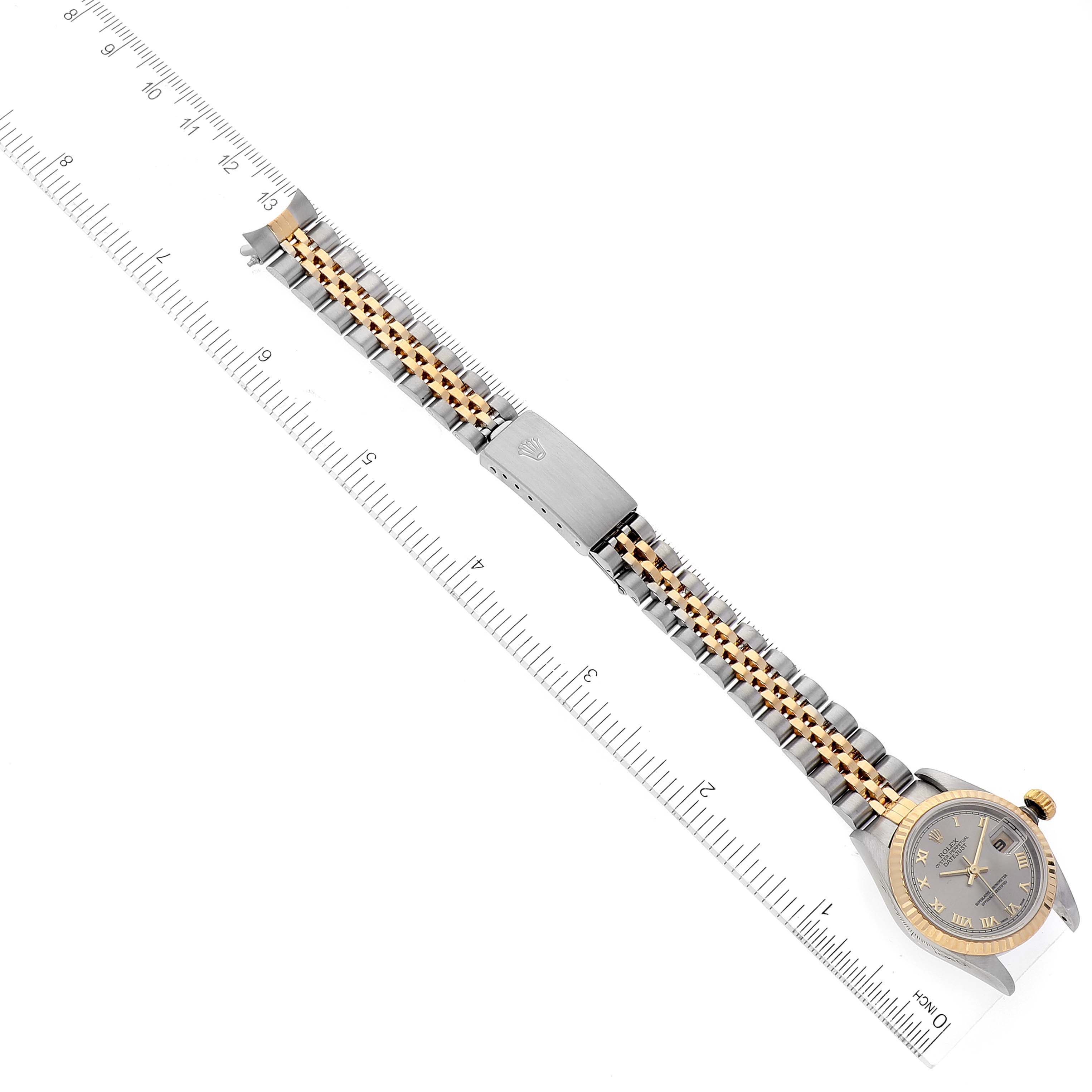 The image shows a top-down view of a Rolex Datejust 79173 Women
s Steel and Gold (two tone) Grey Dial 79173 Women
s Steel and Gold (two tone) Grey Dial watch with its bracelet aligned next to a ruler for measurement.