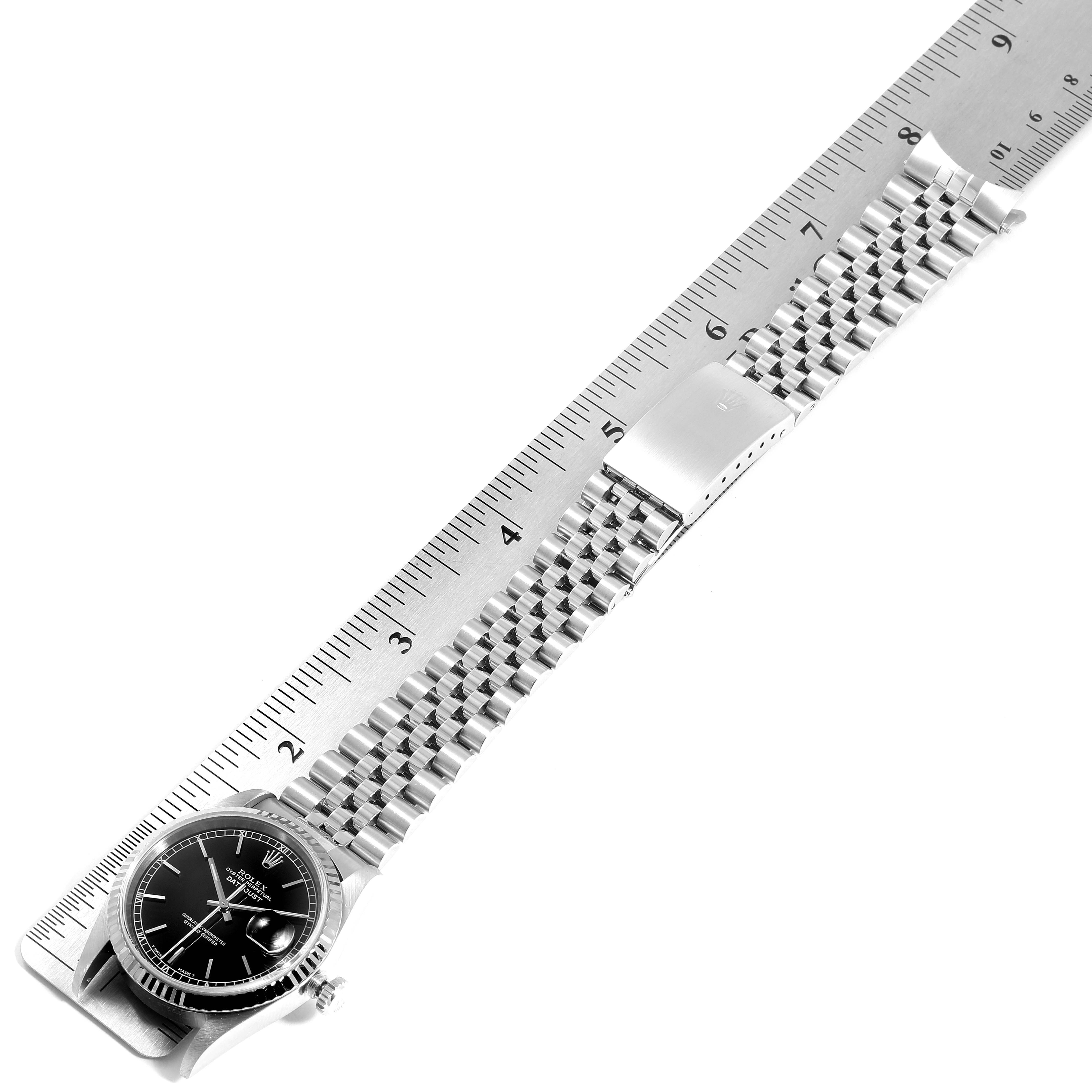 This image shows a Rolex Datejust 16234 Men's Stainless Steel Black Dial 16234 Men's Stainless Steel Black Dial watch laid flat next to a ruler, highlighting the case and bracelet.