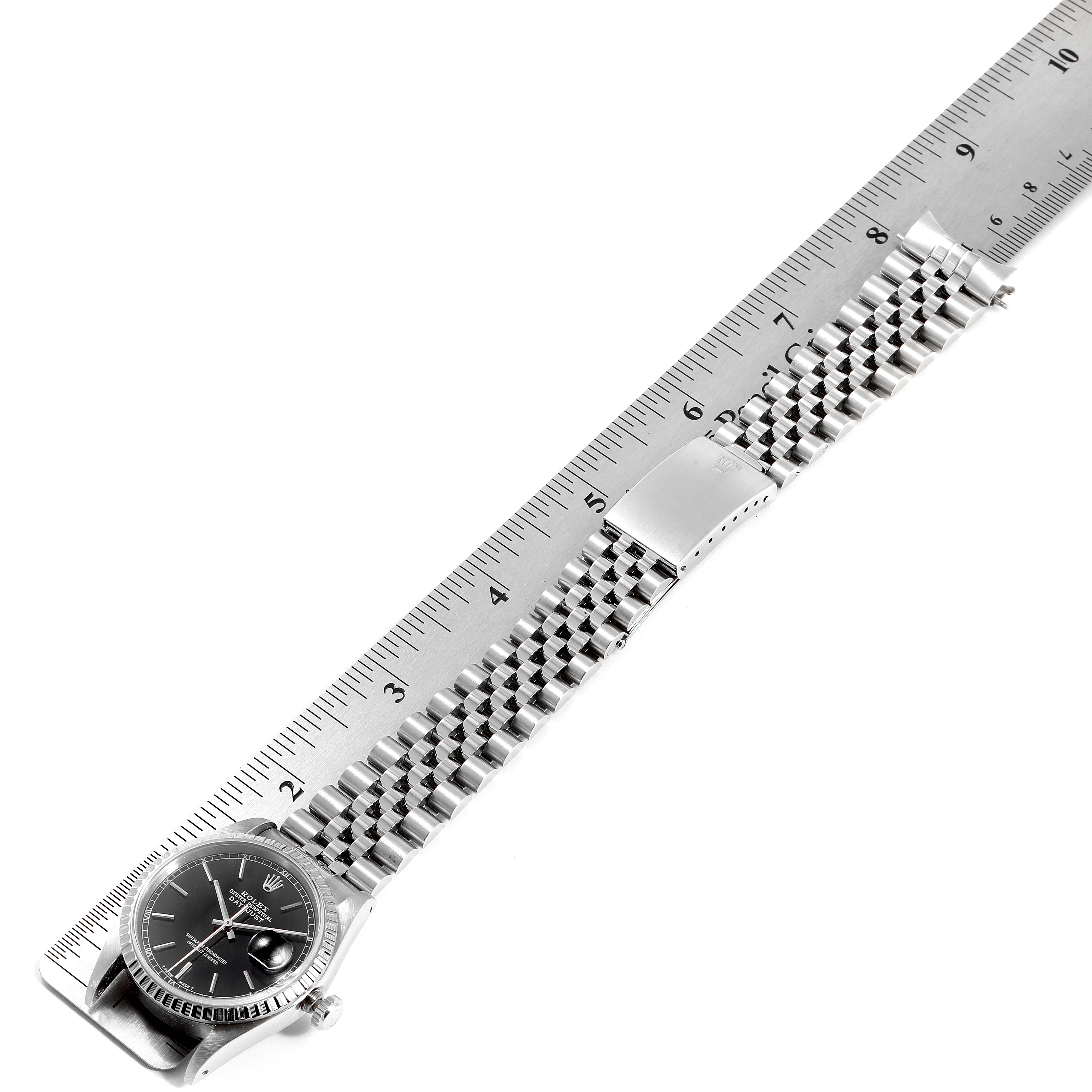 This image shows a Rolex Datejust 16220 Men
s Stainless Steel Black Dial 16220 Men
s Stainless Steel Black Dial watch placed alongside a ruler, displaying the watch face and entire bracelet.