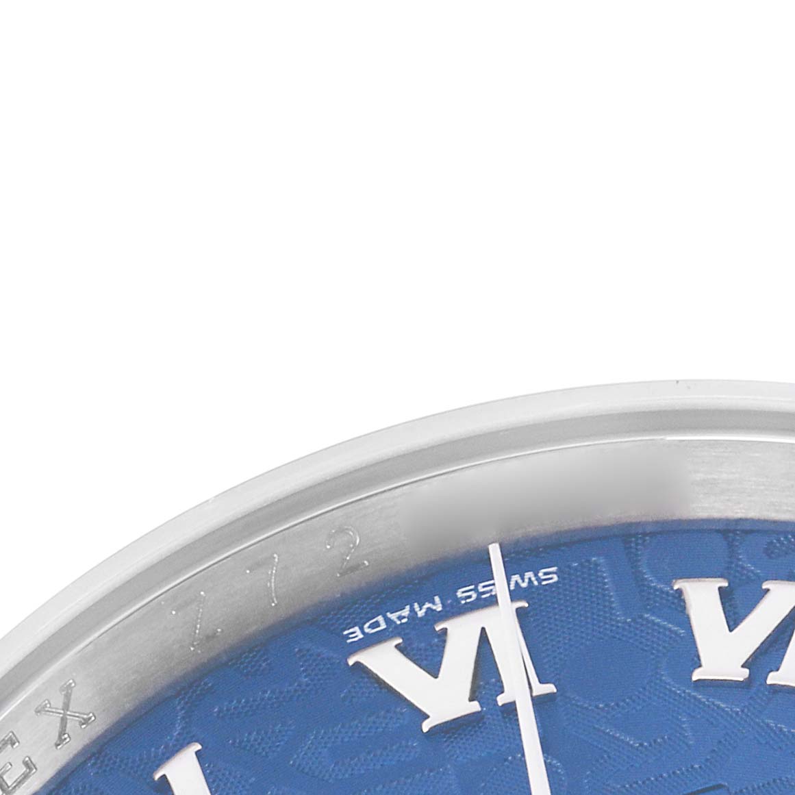 The image shows a close-up of the bezel and part of the dial of a Rolex Datejust 116200 Men
s Stainless Steel Blue Dial watch, highlighting the Roman numeral hour markers on a blue background.
