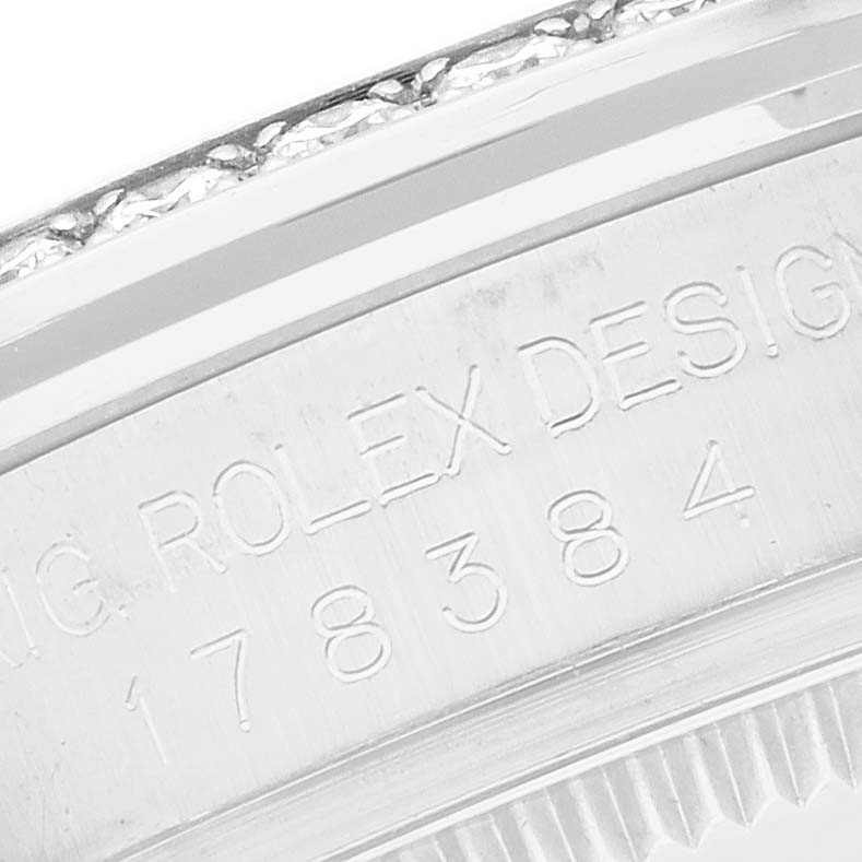 The image shows an angled close-up of the case side of a Rolex Mid-Size 178384 Women
s Stainless Steel Mother of Pearl Dial model, highlighting the engraved "Rolex Design" and its reference number.