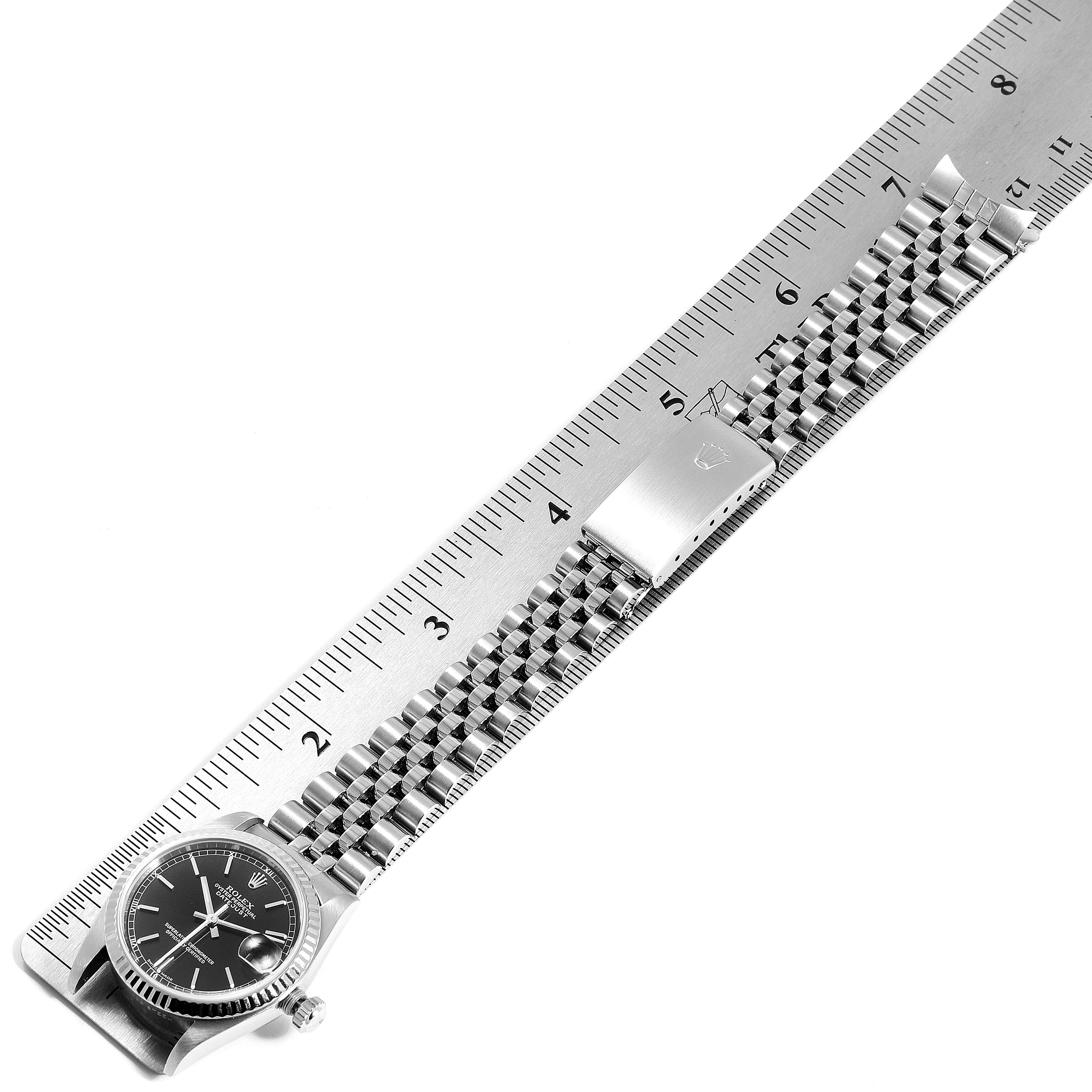 The image shows a Mid-Size Rolex watch positioned horizontally on a ruler, displaying its face, bracelet, and clasp.