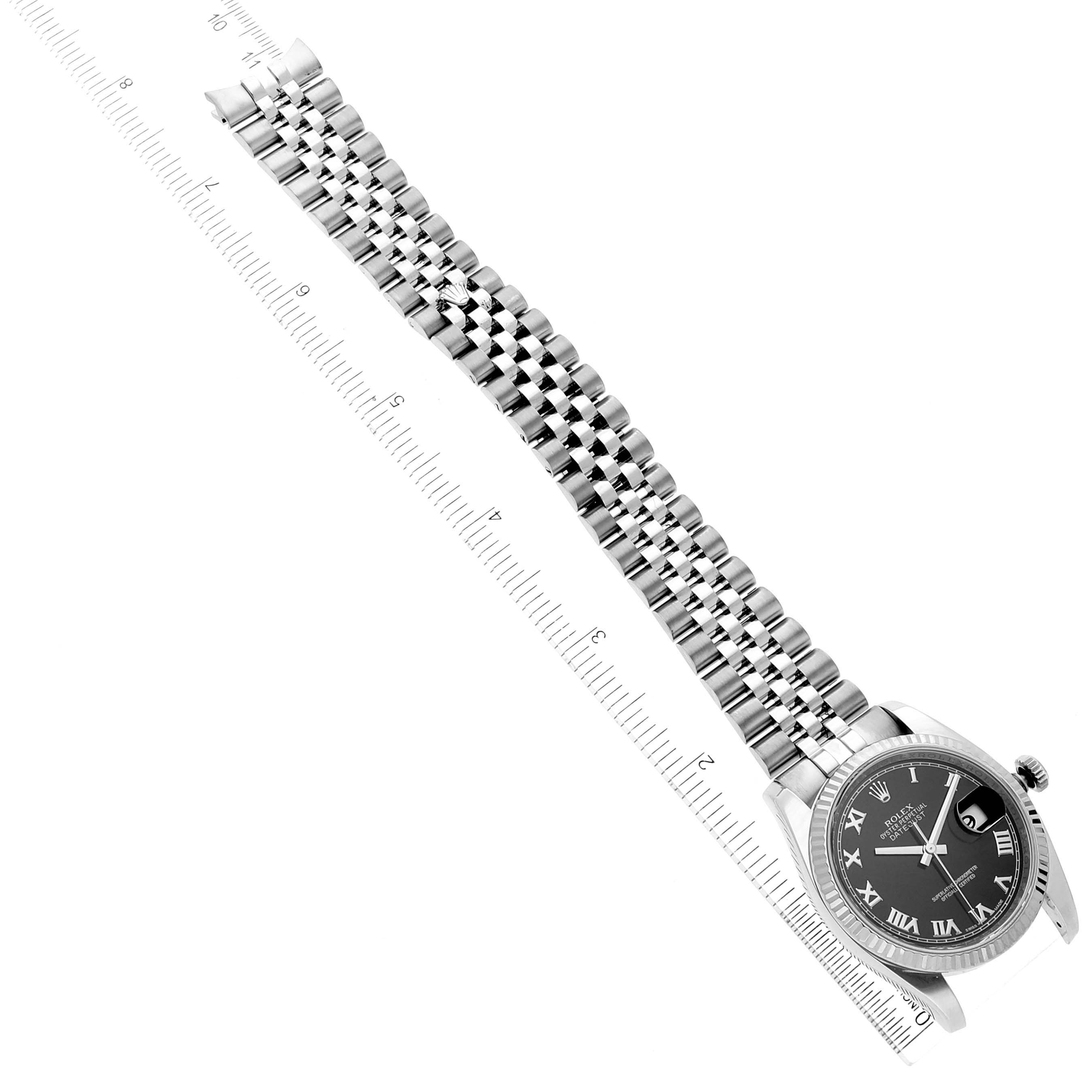 The image shows a Rolex Datejust 116234 Men
s Stainless Steel Black Dial 116234 Men
s Stainless Steel Black Dial watch from an angled top view, highlighting the face, bracelet, and ruler for scale.