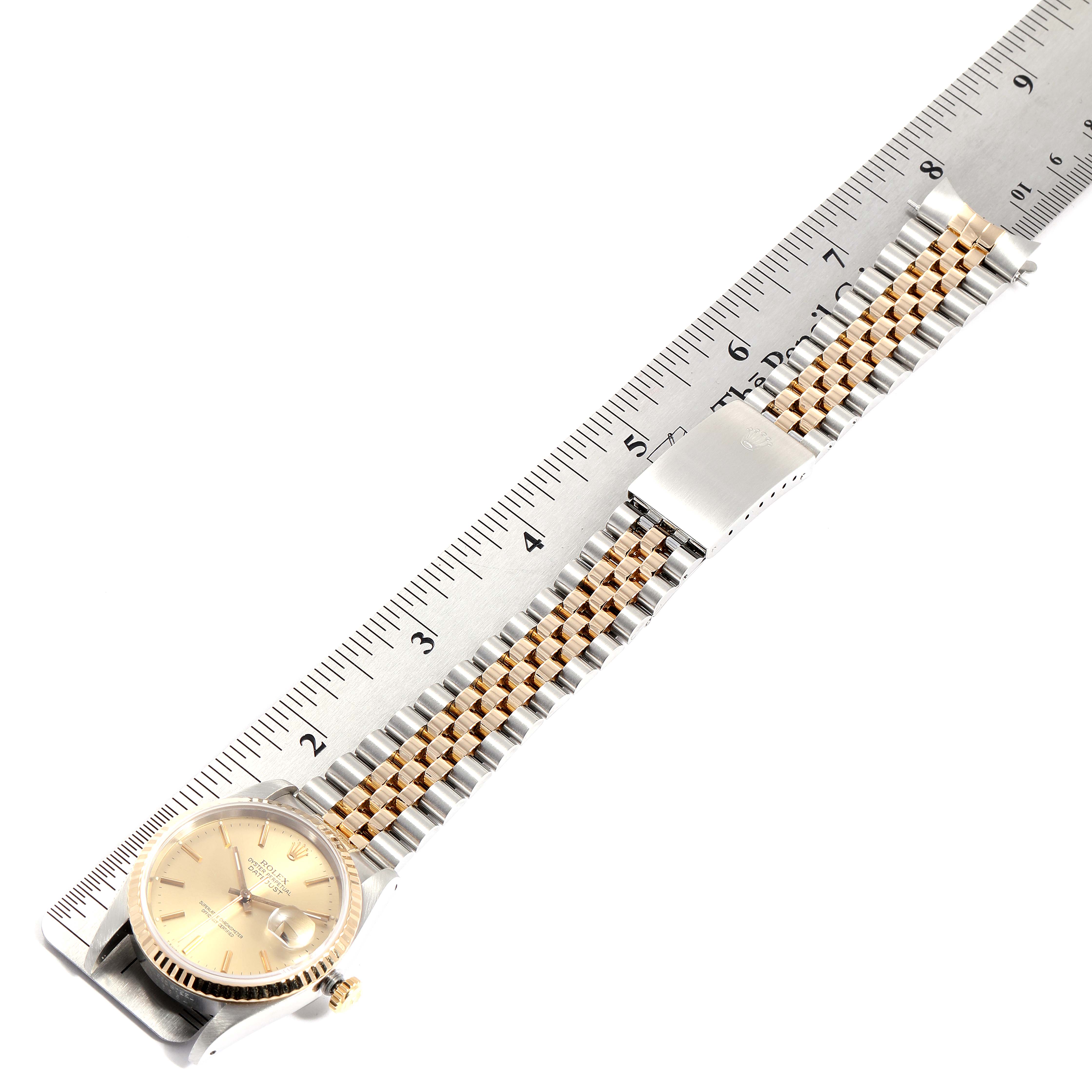 This image shows a Rolex Datejust 16233 Men
s Steel and Gold (two tone) Champagne Dial 16233 Men
s Steel and Gold (two tone) Champagne Dial watch laid flat, showcasing the face, bezel, case, crown, and bracelet alongside a ruler for scale.