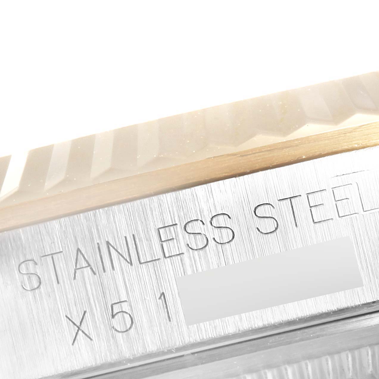 This close-up image of a Rolex Datejust 16233 Men's Steel and Gold (two tone) Champagne Dial 16233 Men's Steel and Gold (two tone) Champagne Dial watch shows the fluted bezel and the "STAINLESS STEEL" engraving on the case side.