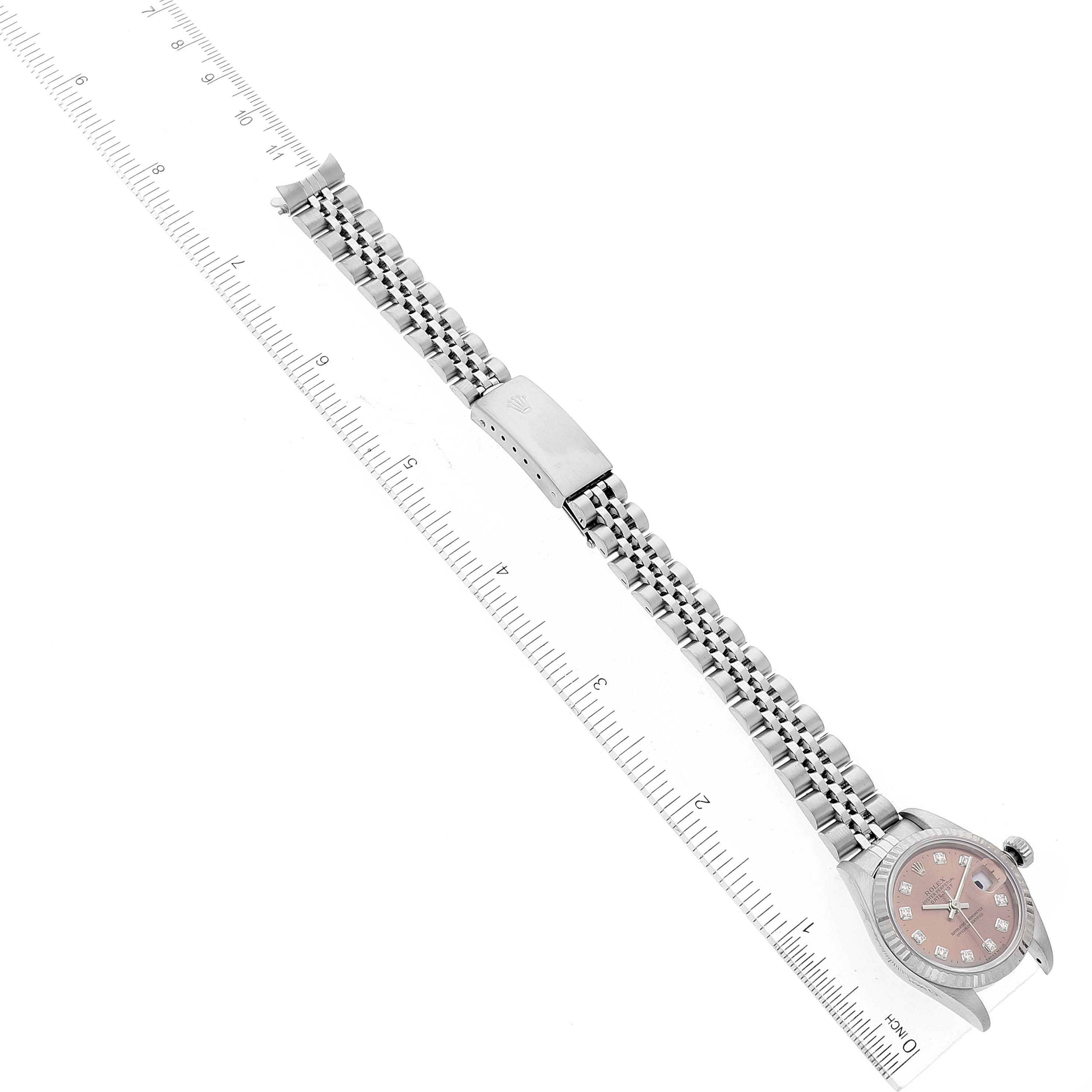 The Rolex Datejust 79174 Women
s Stainless Steel Pink Dial 79174 Women
s Stainless Steel Pink Dial watch is shown lying flat with the full bracelet extended and aligned next to a ruler for measurement.