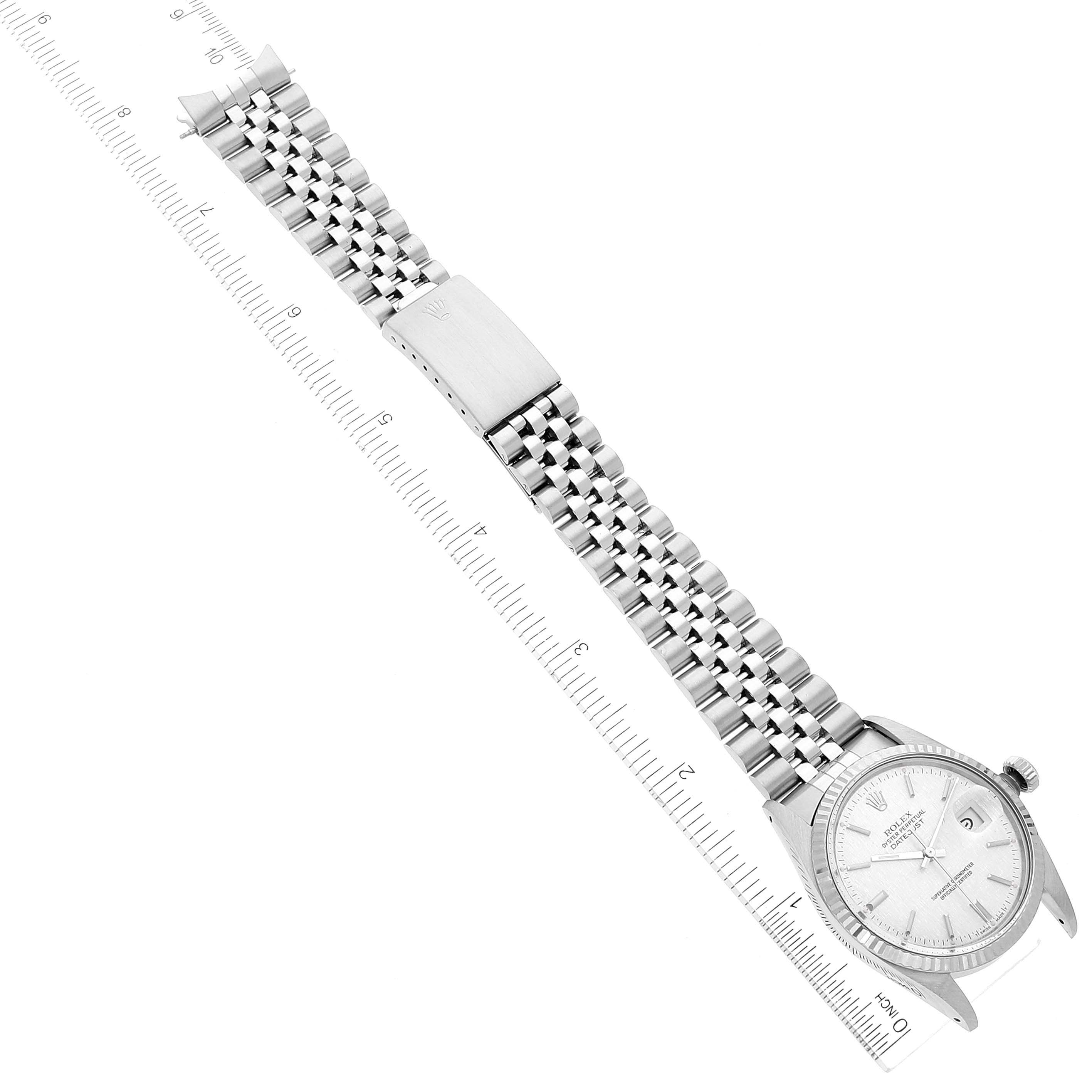 The image shows a top-down angle of a Rolex Datejust 16014 Men
s Stainless Steel Silver Dial 16014 Men
s Stainless Steel Silver Dial watch, highlighting its face, bezel, and metal bracelet with a ruler for scale.