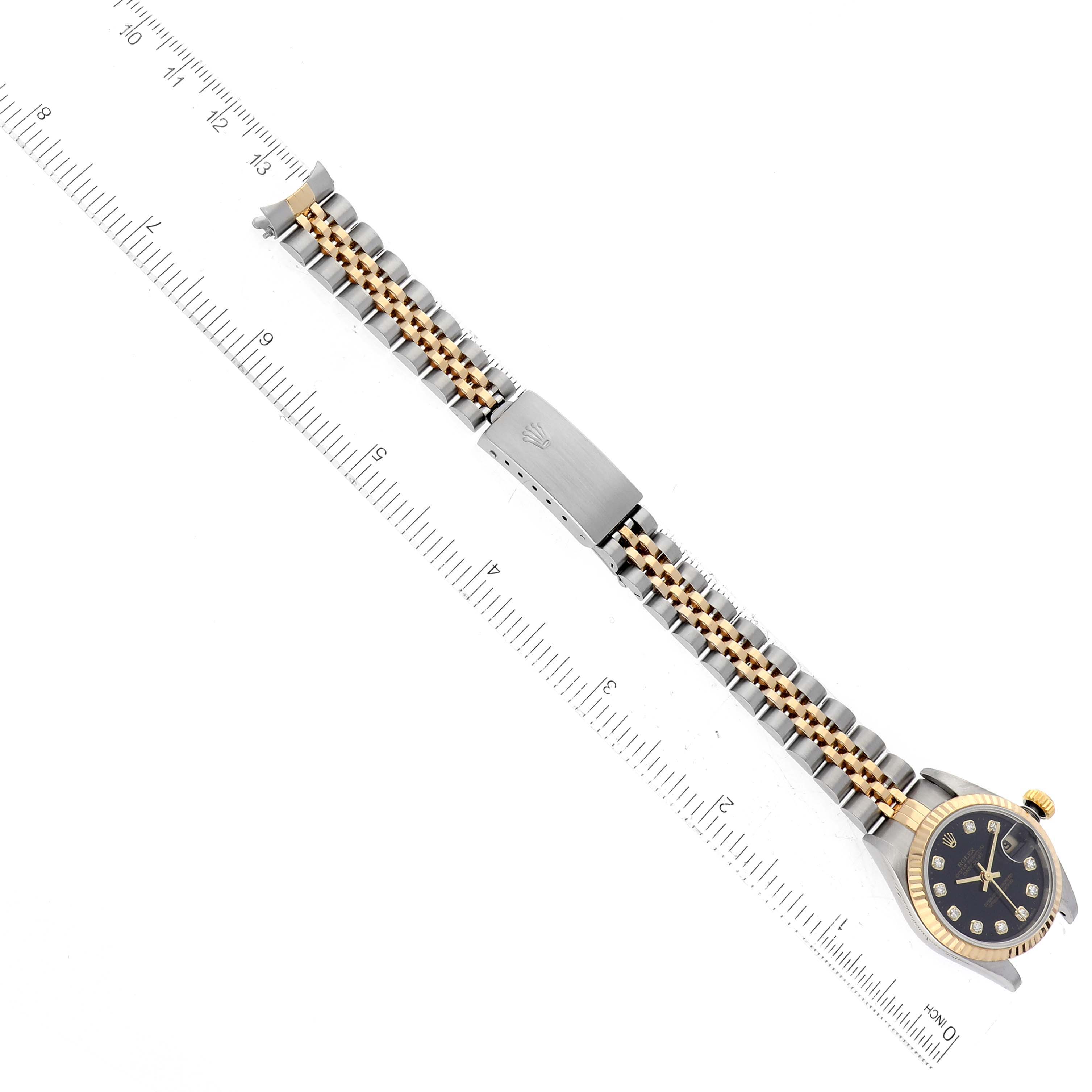 The image shows a Rolex Datejust 79173 Women's Steel and Gold (two tone) Black Dial 79173 Women's Steel and Gold (two tone) Black Dial watch laid flat with a ruler underneath, displaying the bracelet and a partial view of the watch face.