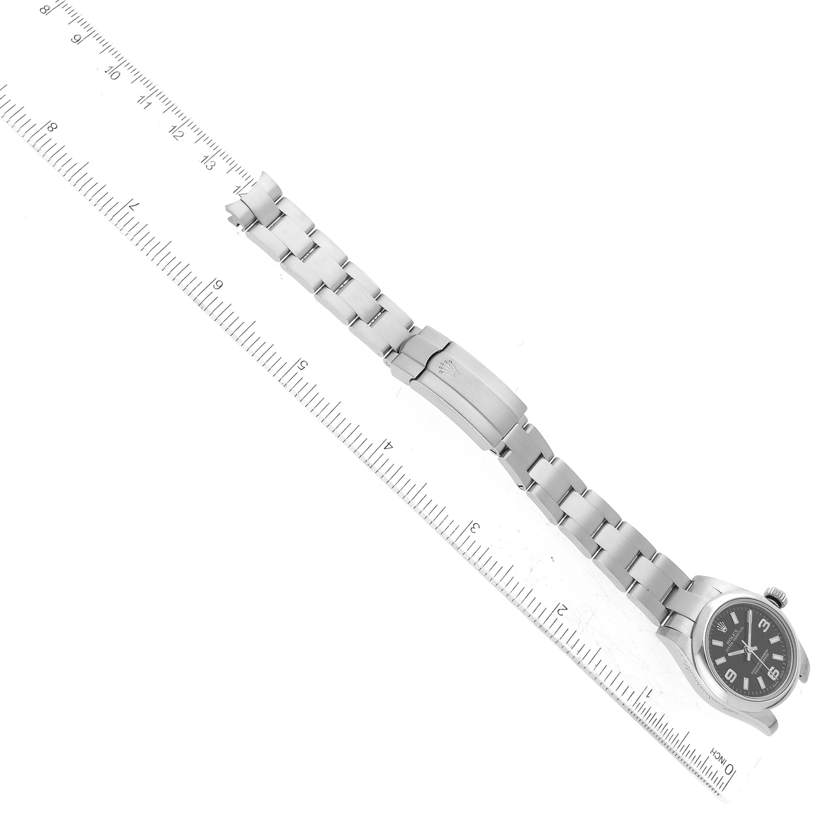 The Rolex Oyster Perpetual 176200 Women's Stainless Steel Black Dial 176200 Women's Stainless Steel Black Dial watch is shown at an oblique angle, displaying the full length of the bracelet and the face, next to a ruler for scaling.