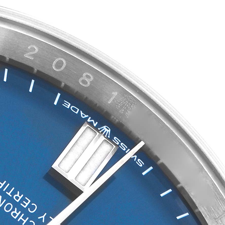 The image shows a close-up of the dial and bezel of a Rolex Oyster Perpetual 126000 Men
s Stainless Steel Blue Dial watch, highlighting the blue face and markers.