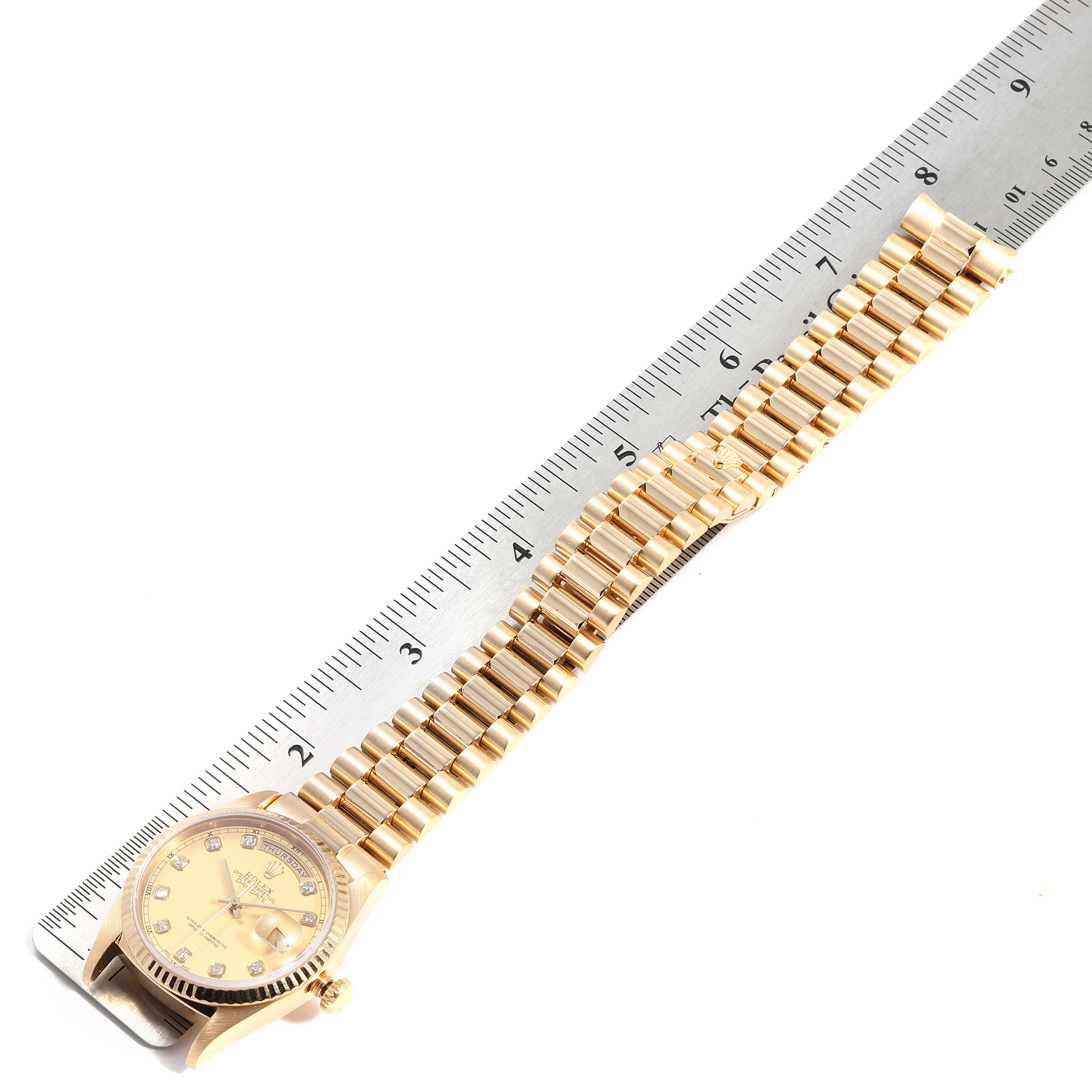 The Rolex President 18038 Men's Yellow Gold Champagne Dial 18038 Men's Yellow Gold Champagne Dial model watch is shown from an aerial view, showcasing its face and full bracelet length next to a ruler.