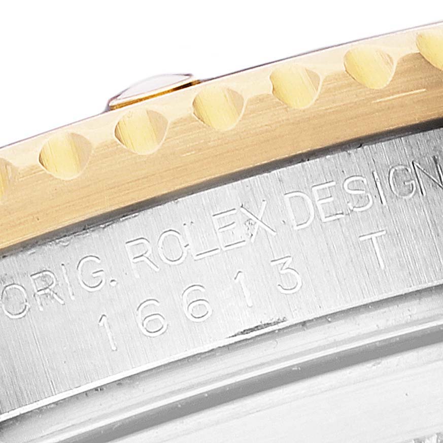 The image shows a close-up angle of the bezel and engraved case of a Submariner model by Rolex, displaying the design number 16613.