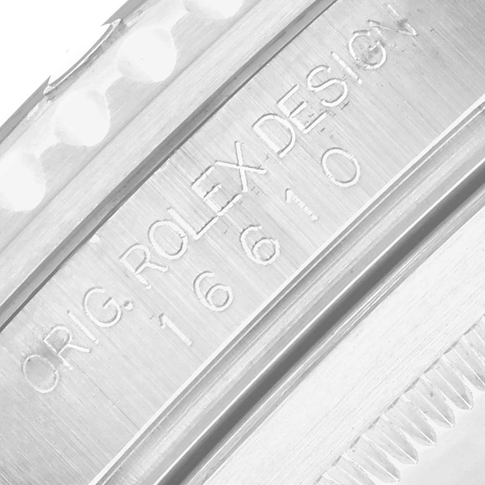 The image shows a close-up of the engravings on the side of the case of a Rolex Submariner 16610 Men
s Stainless Steel Black Dial, including a partial view of the bezel.